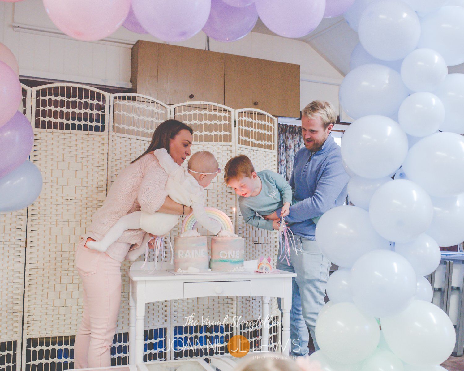 Family blowing candles out at baby's first birthday party
