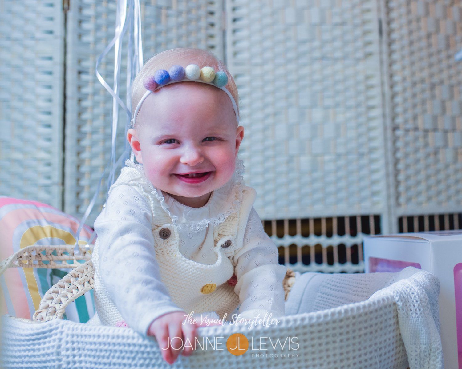 baby girl with huge smily in bassonette with rainbow pillow