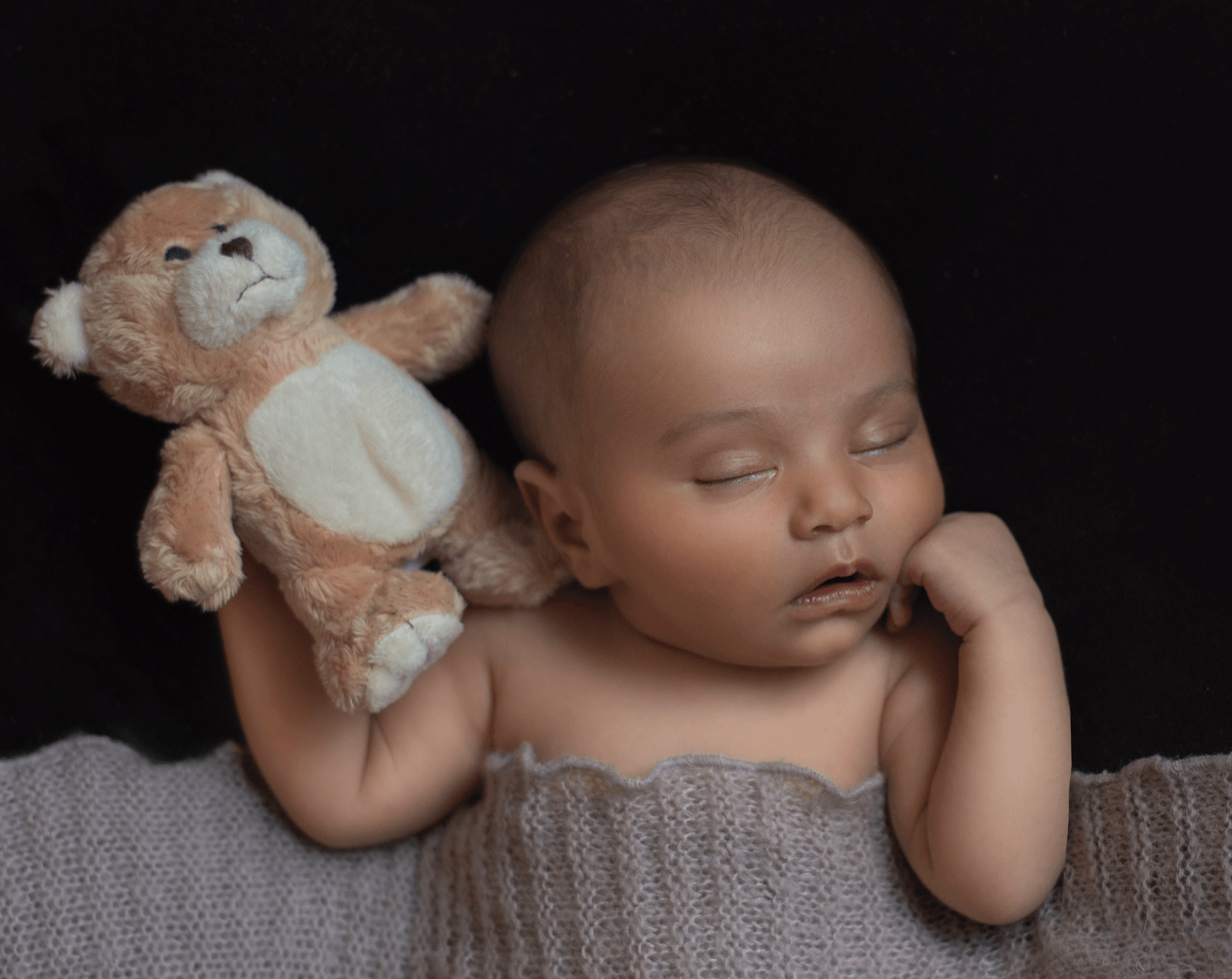 Baby asleep under blanket holding teddy bear