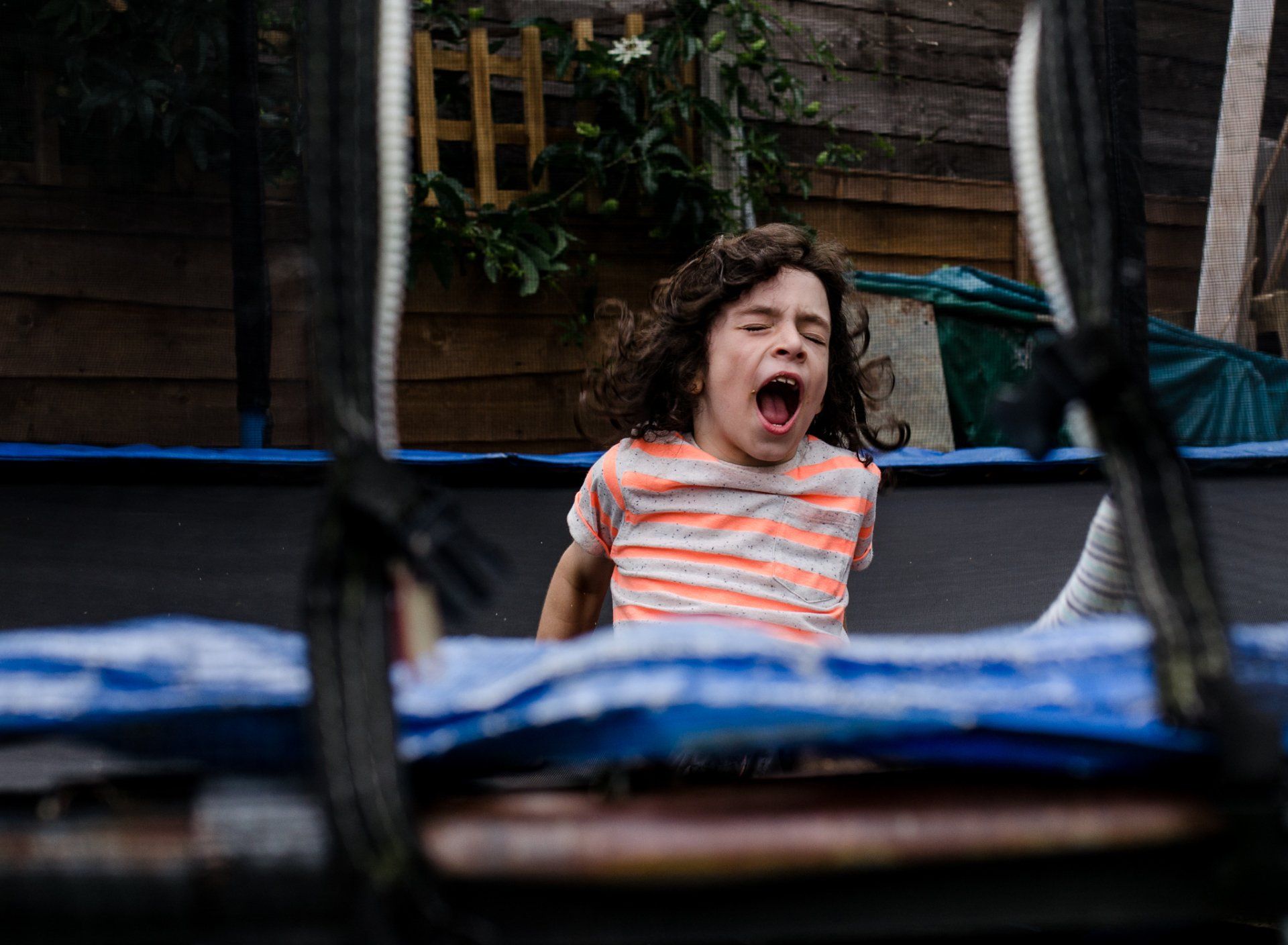 Young boy with pained expression falling on trampoline