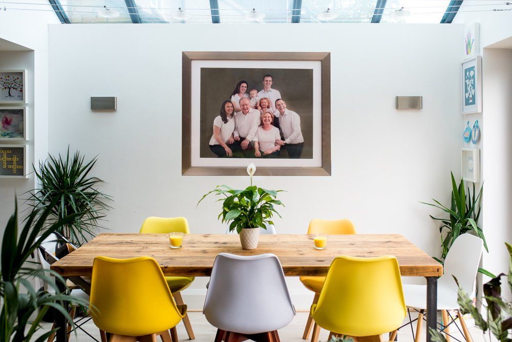 Huge framed photograph of a large family on a wall in beautiful modern white home with splashes of yellow