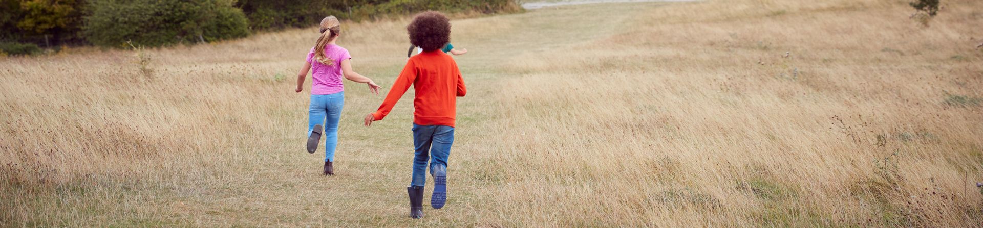 Children running across a grassy field.