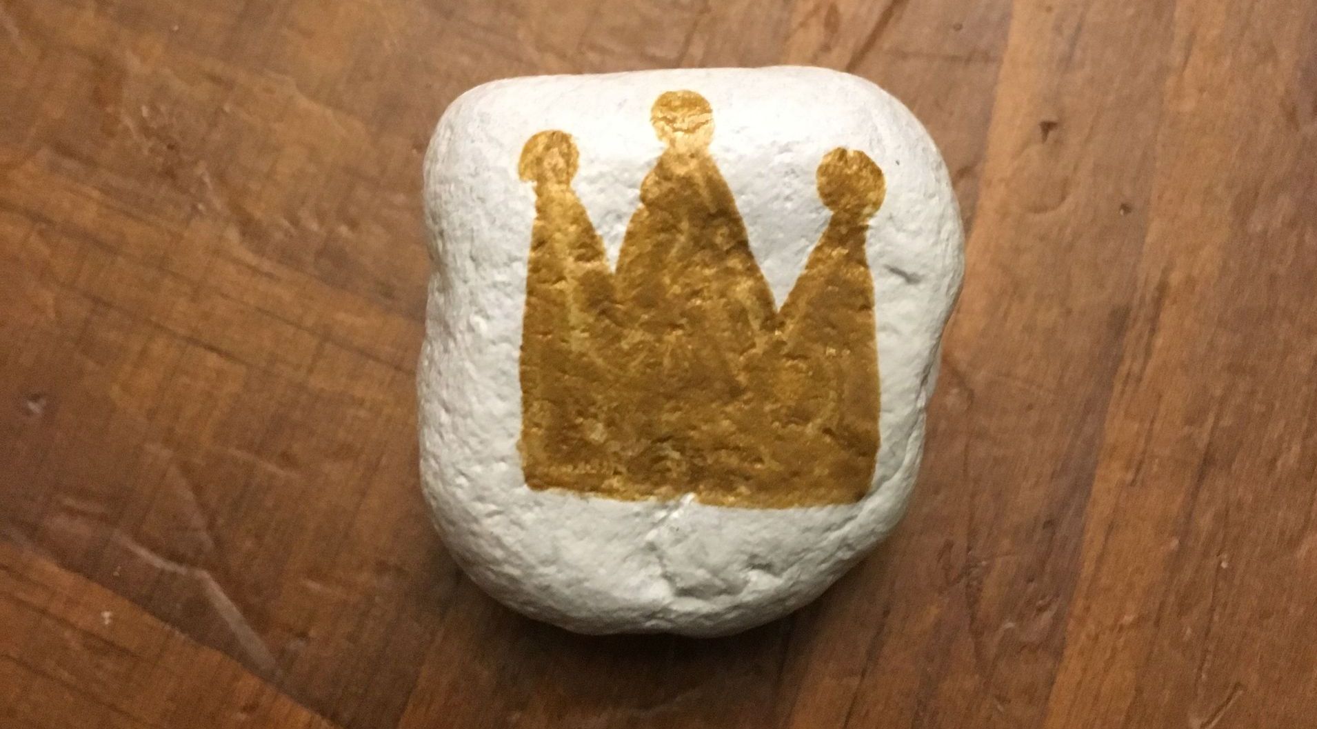A white stone with a gold crown painted on it.