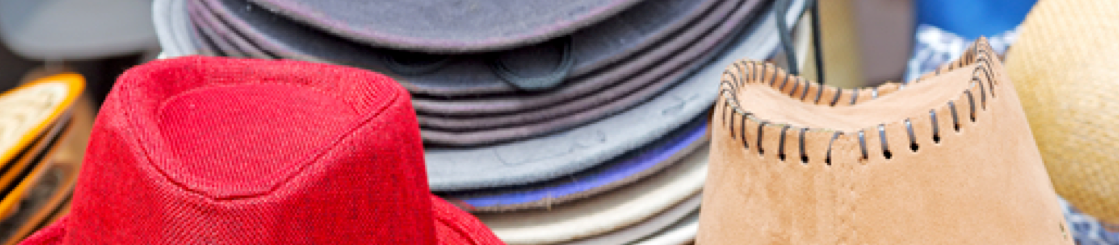 Photo of the top of hates in the foreground with piles of hats in the background