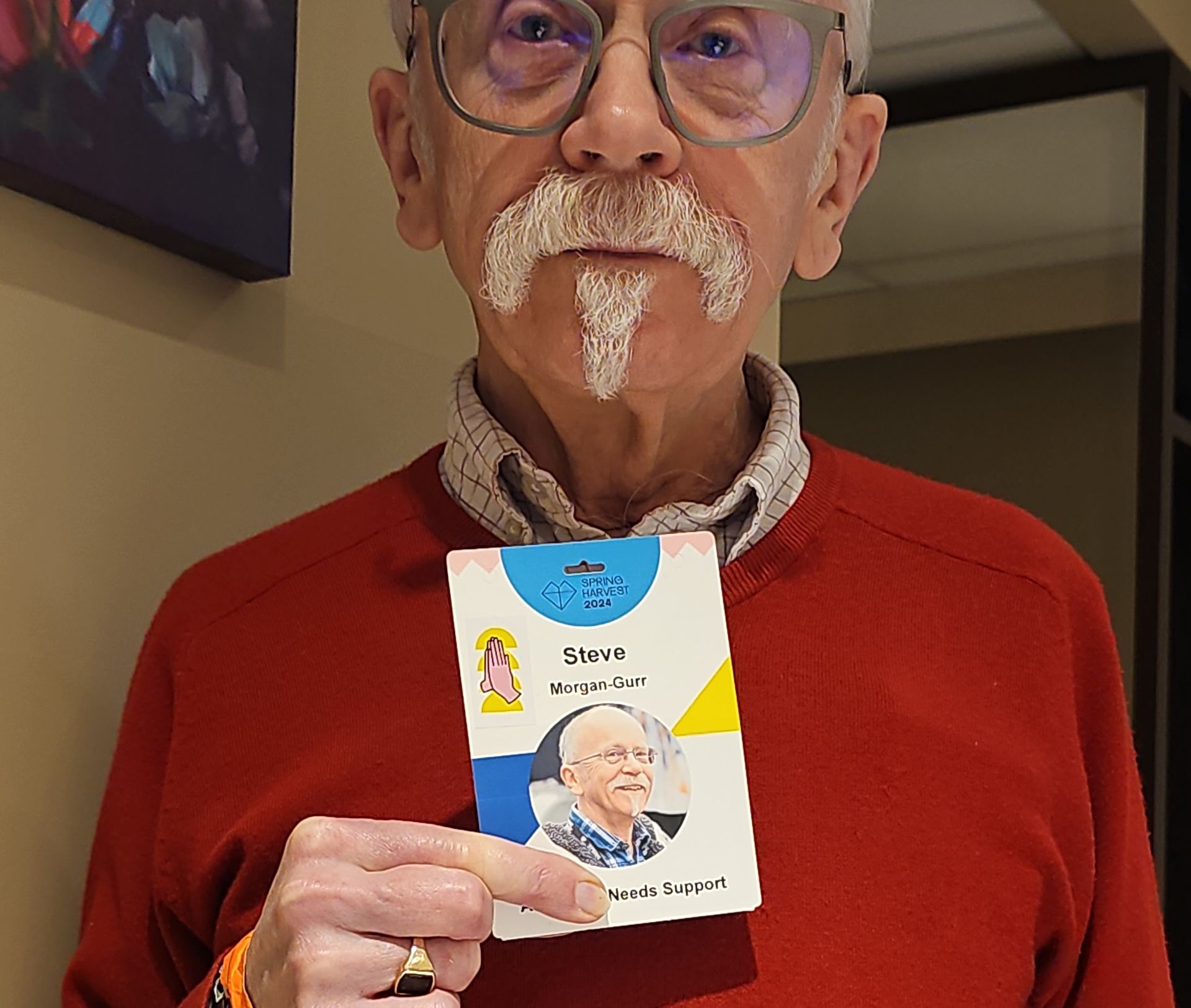 A photo of Steve holding up his Spring Harvest team badge. He has his finger over over part of his title so it reads