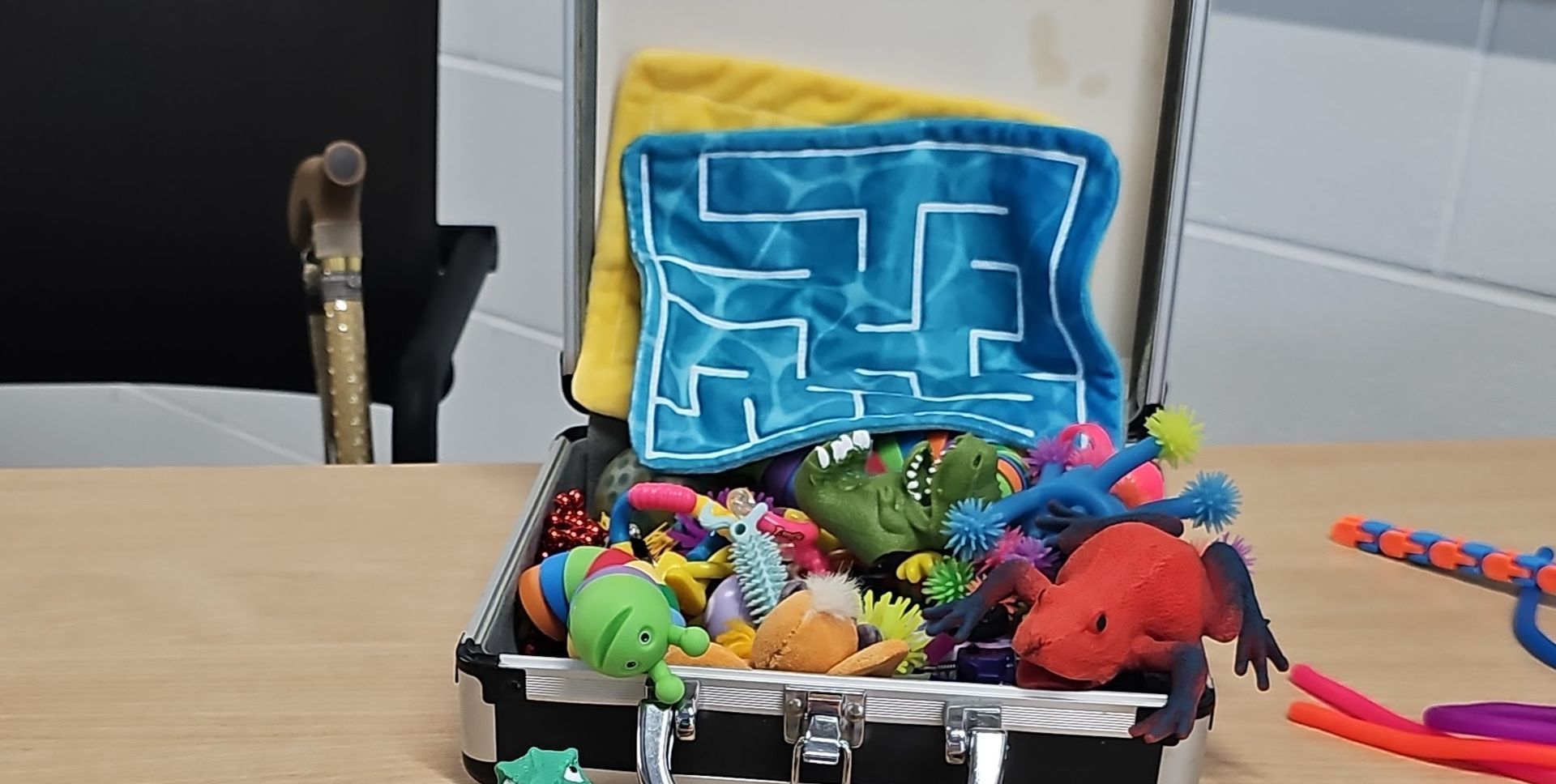 A box of many different fidget toys that are spilling out onto the table.