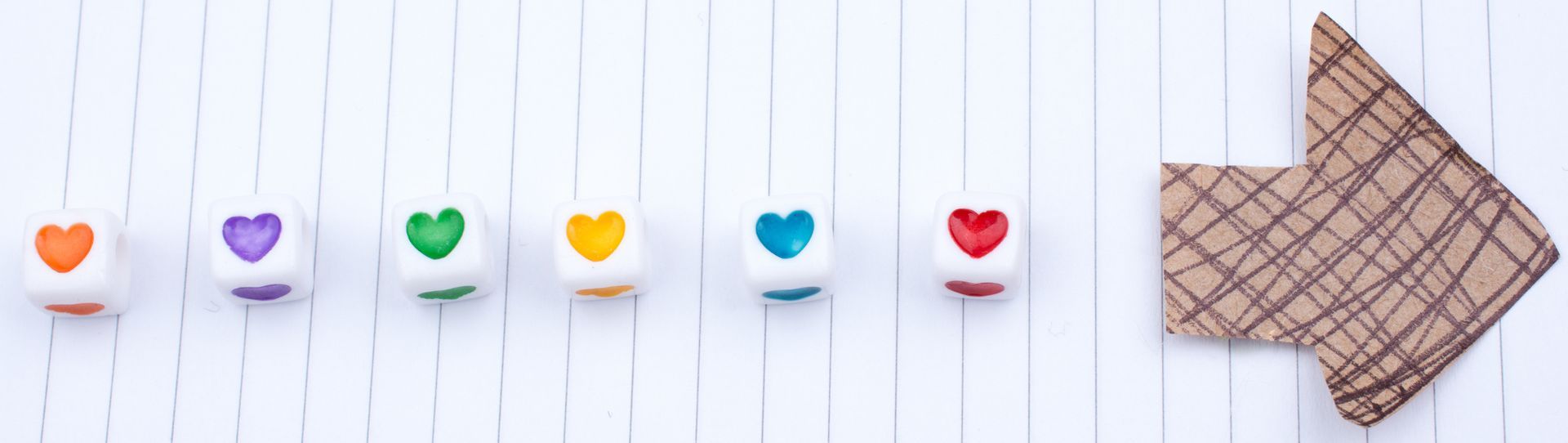 A row of cubes with different coloured hearts on them, there is a cardboard arrow pointing to the right on the right hand side.