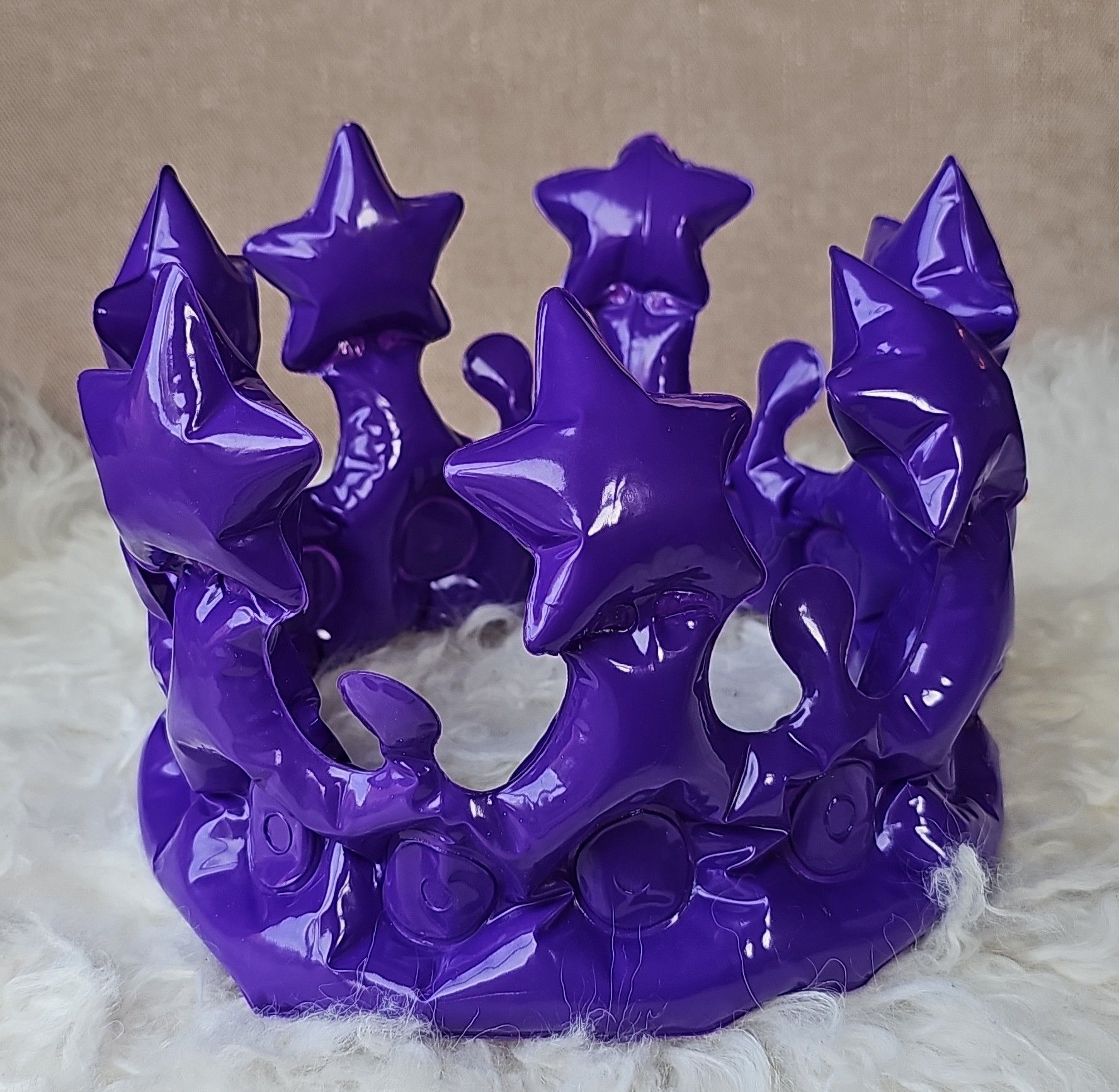 An inflatable purple crown sitting on a furry cushion