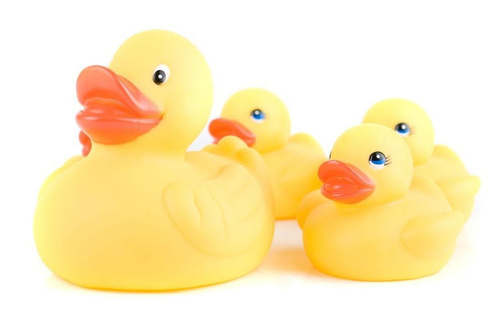 One larger rubber duck with three smaller ones behind it.