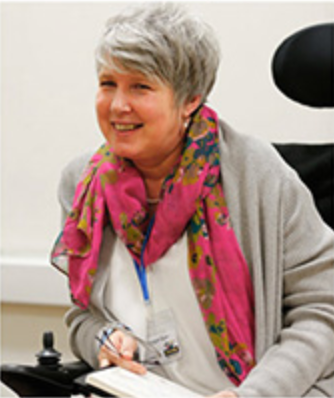 Picture of Kay leaning forward in her wheelchair whilst teaching.