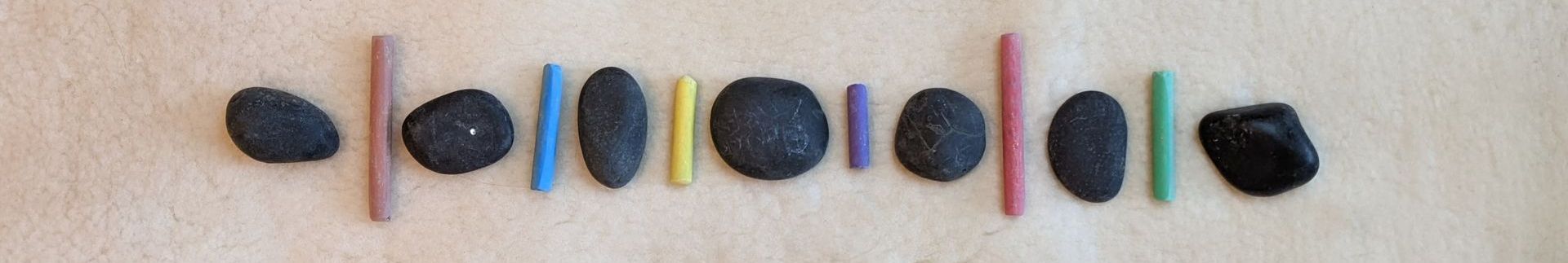 Line of alternating black stones and coloured chalk sticks.