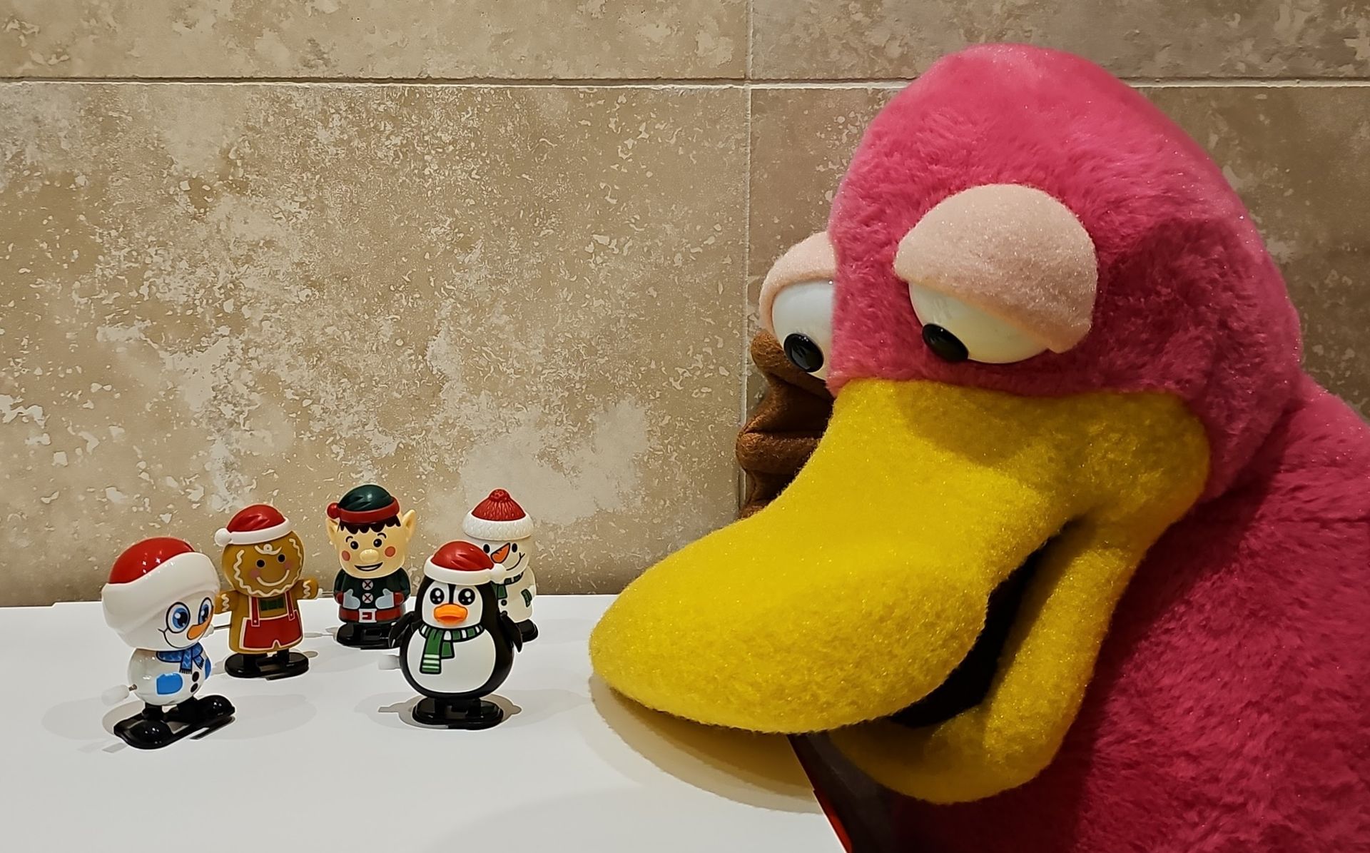 Theo the Pink platypus puppet looking at some wind up, walking toys.