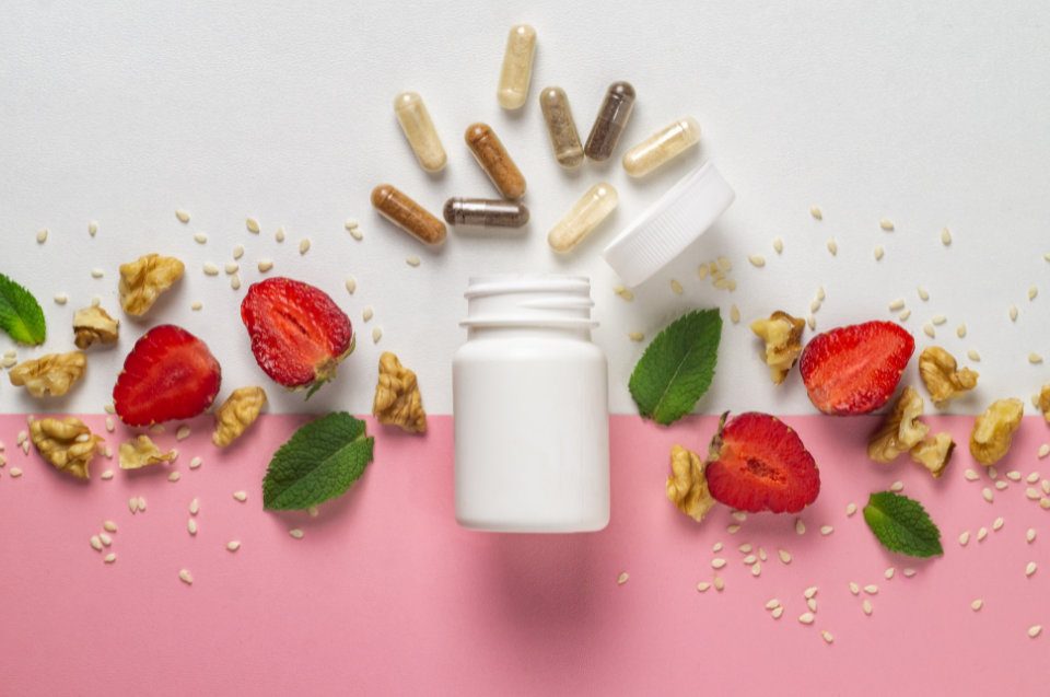 Darstellung von Vitamin Kapseln neben ein paar geschnittenen Erdbeeren.