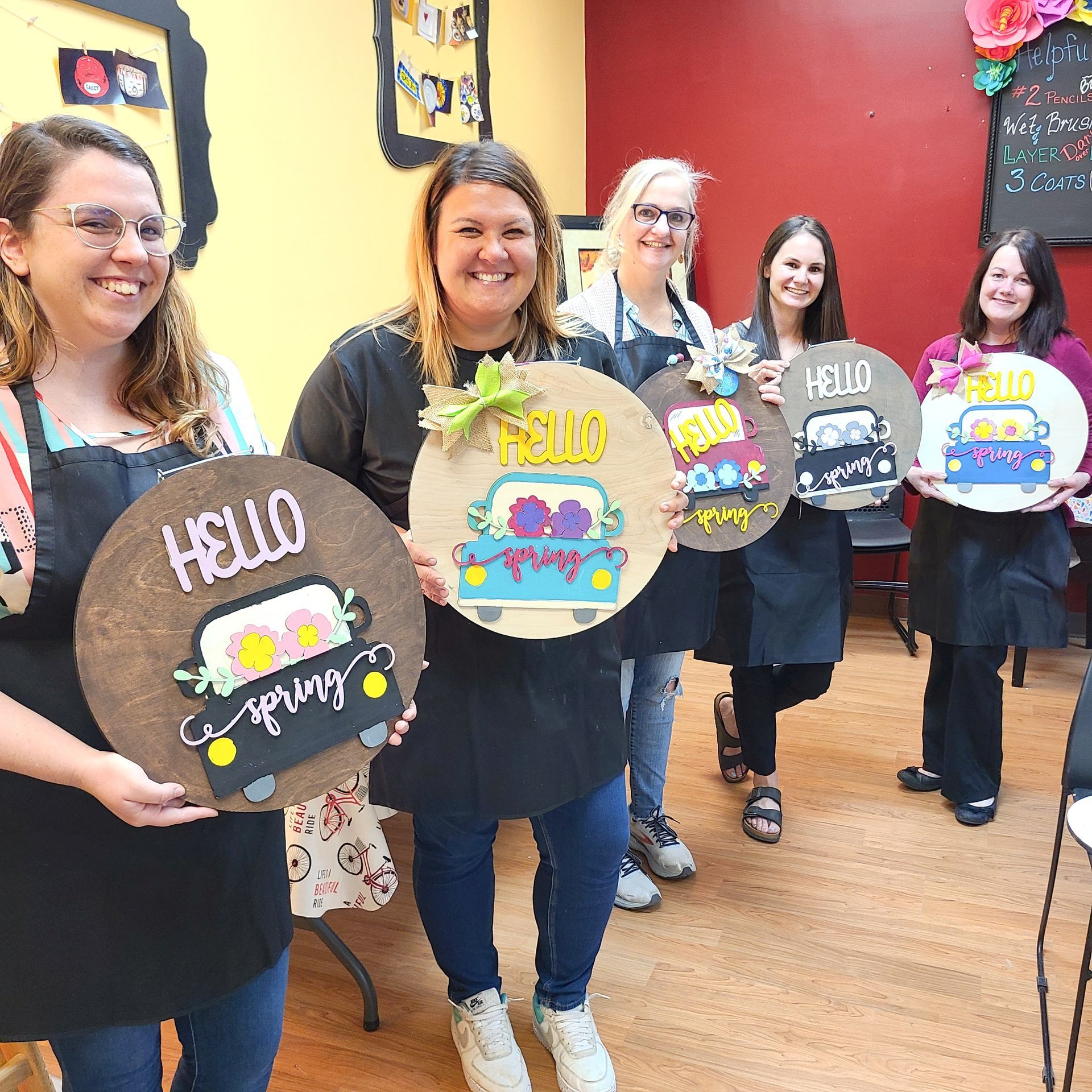 people at a paint party holding spring theme signs they created
