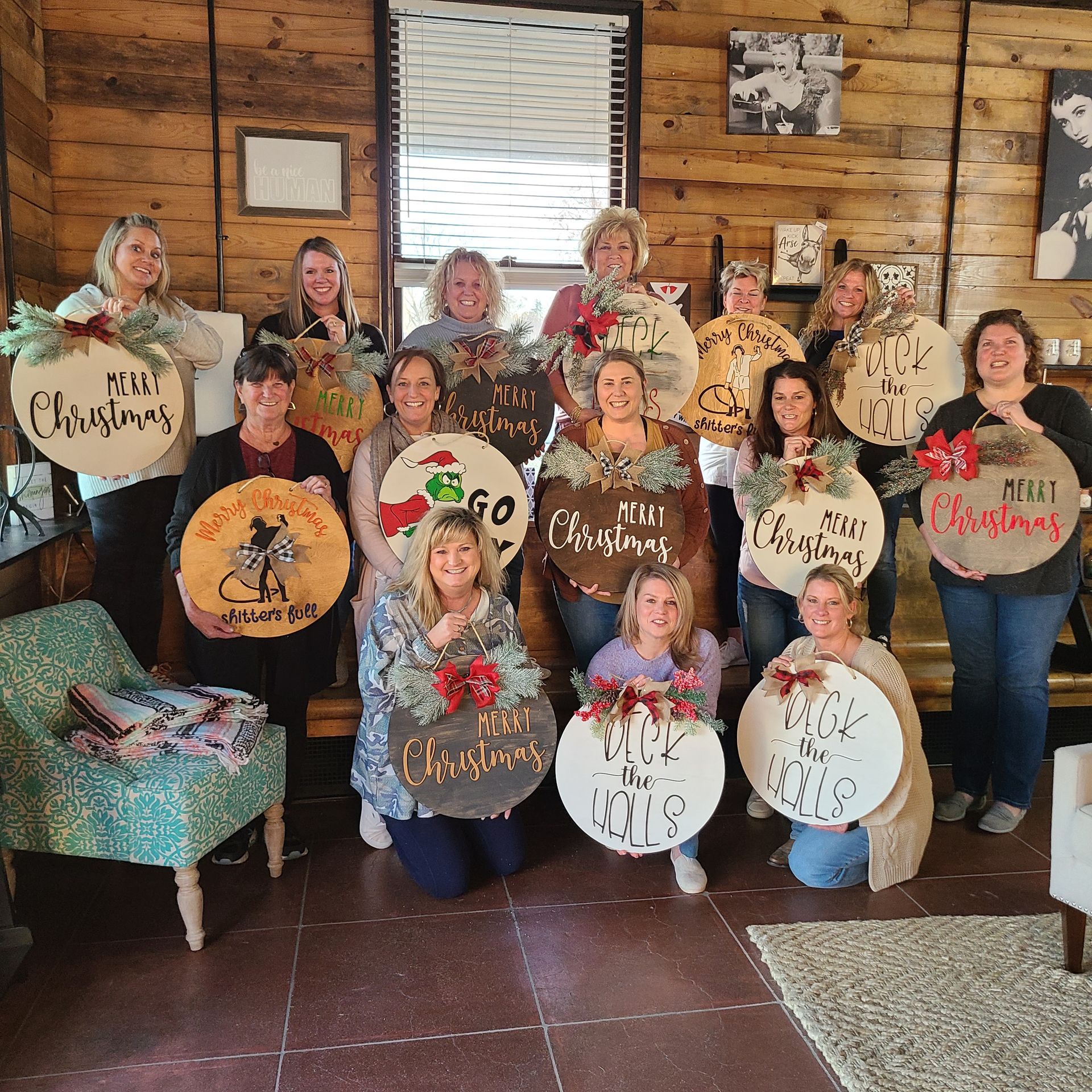 people at a paint party holding wooden signs they created