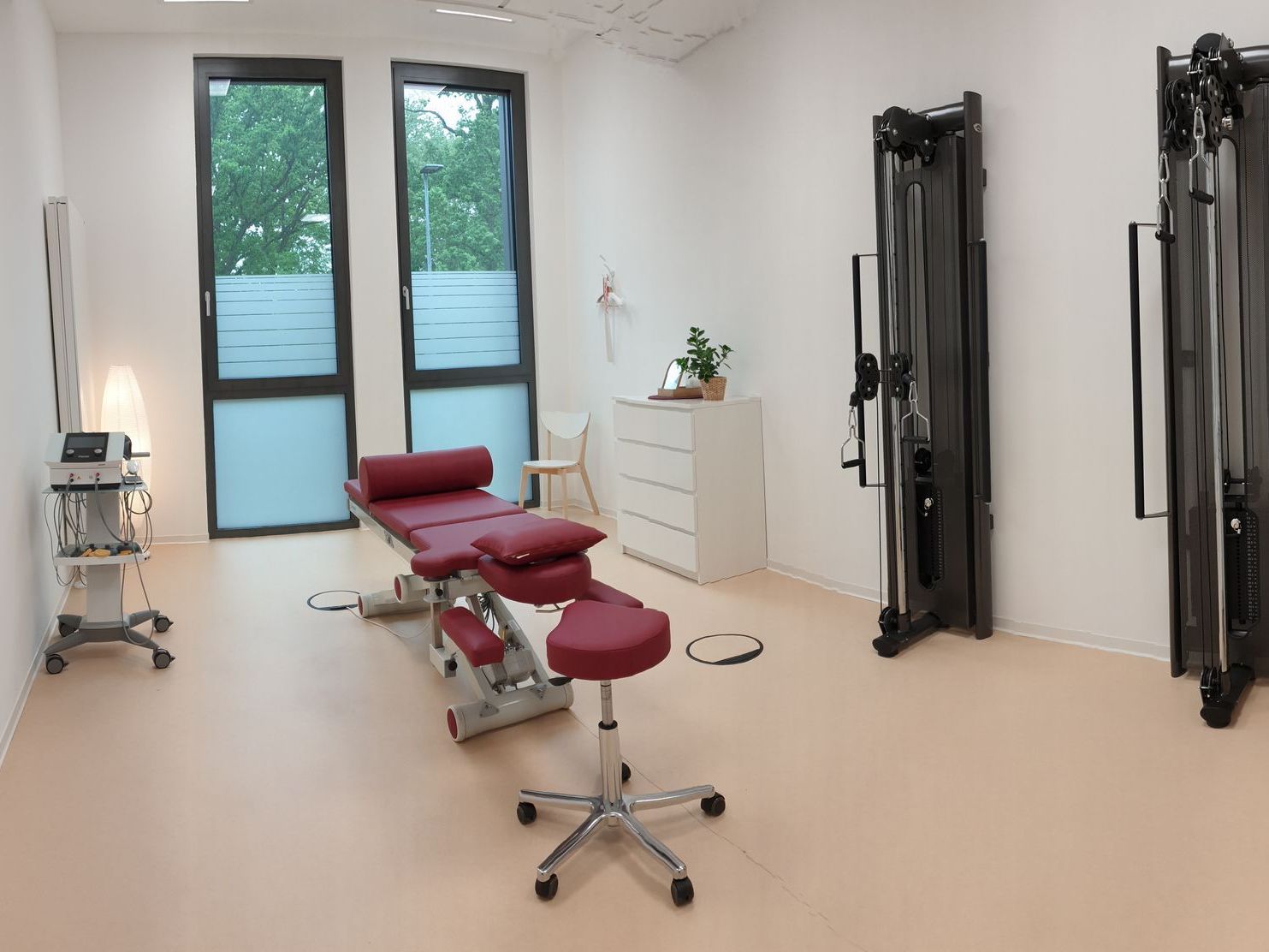 Heller Behandlungsraum mit Therapieliege, Trainingsgeräten und medizinischer Ausstattung.
