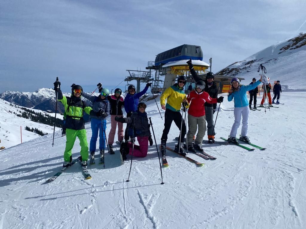 Gruppe von Skifahrern mit Skiern und Stöcken vor einer Bergstation im Schnee.