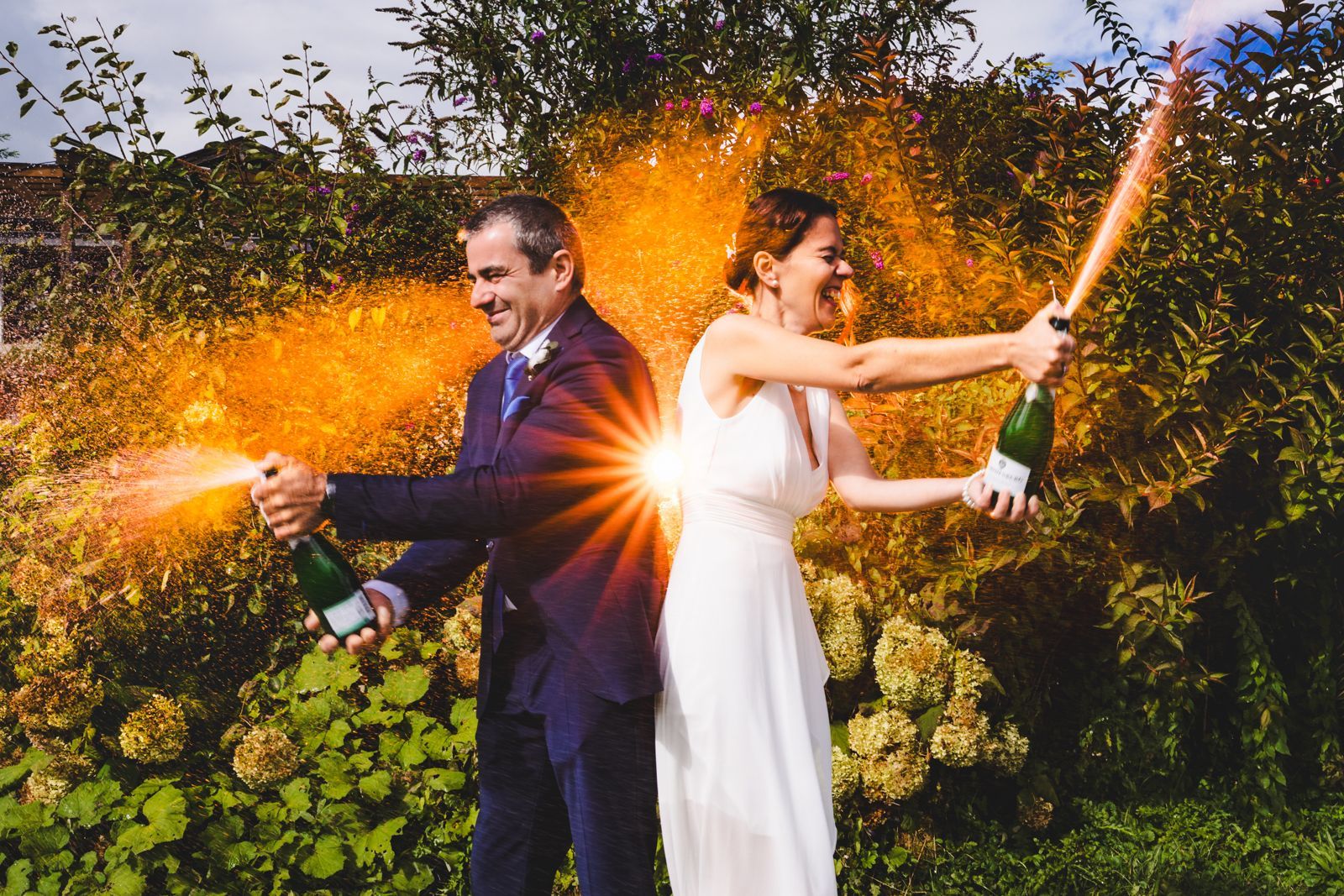 hochzeitspaar spritzt sekt orangenes hintergrundlicht geblitzt