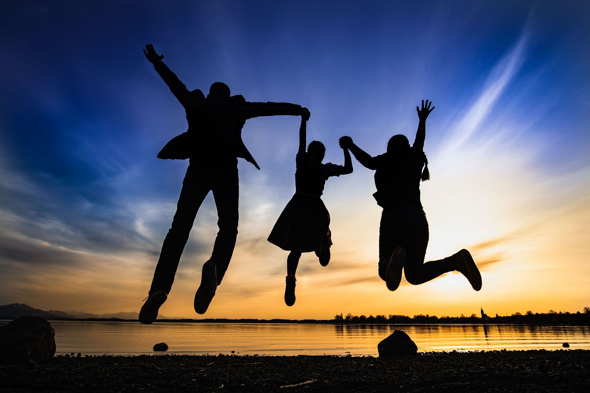 familie springt am chiemsee in die luft silhouette