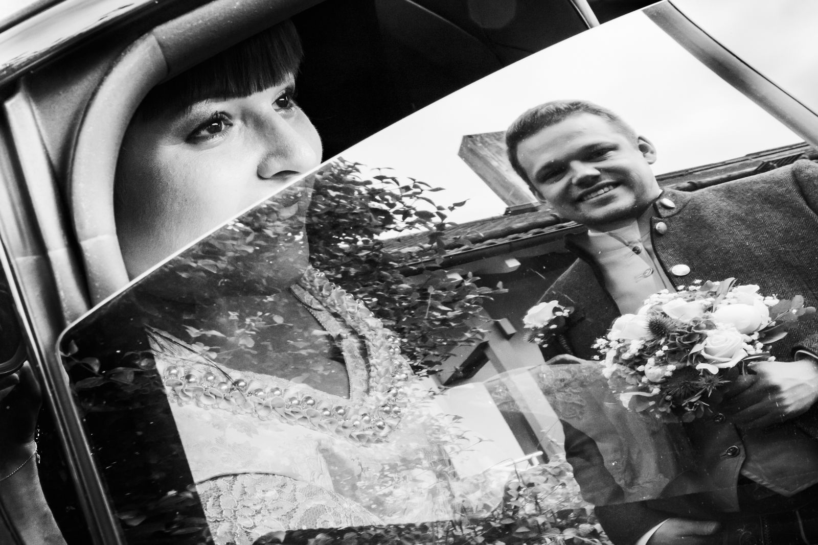 hochzeit im chiemgau brautpaar schaut sich durch geöffnetes fenster eines autos an