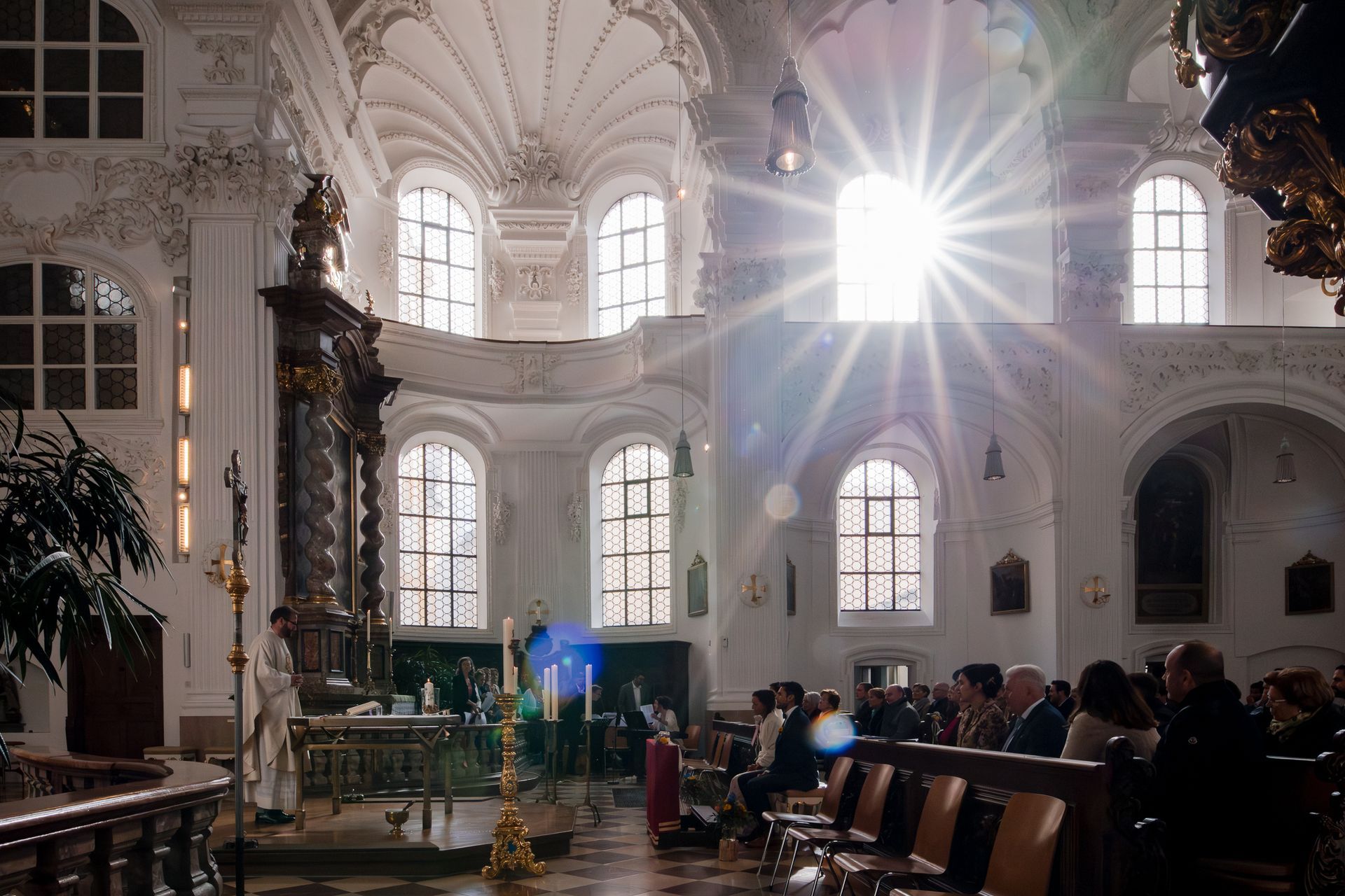 sonne scheint während hochzeit durchs fenster in die kirche st. magdalena in altötting und es ensteht ein blendenstern