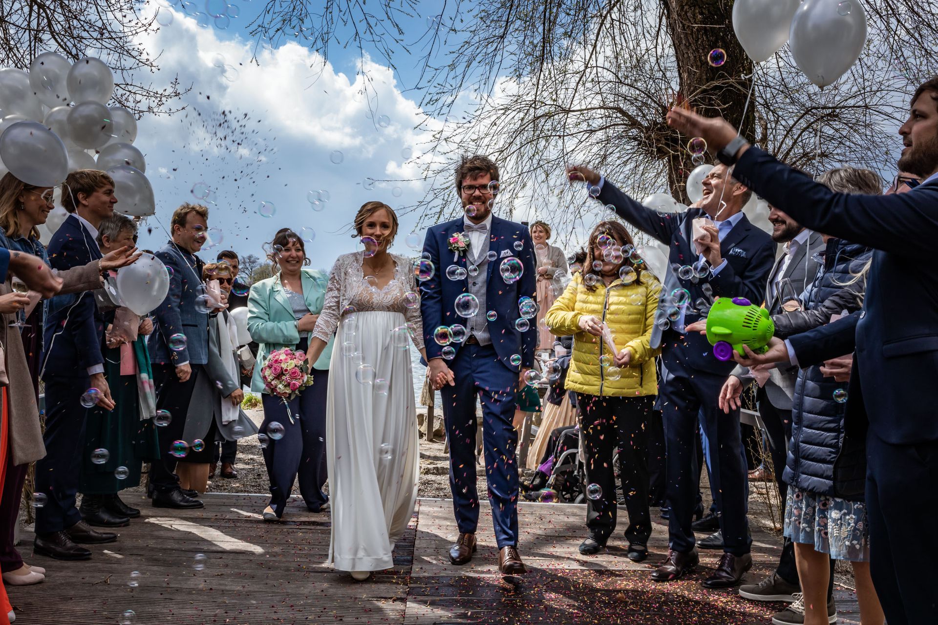 strandbad uebersee chiemsee hochzeitsfotograf andrea kuehl brautpaar laeuft spalier durch seifenblasen