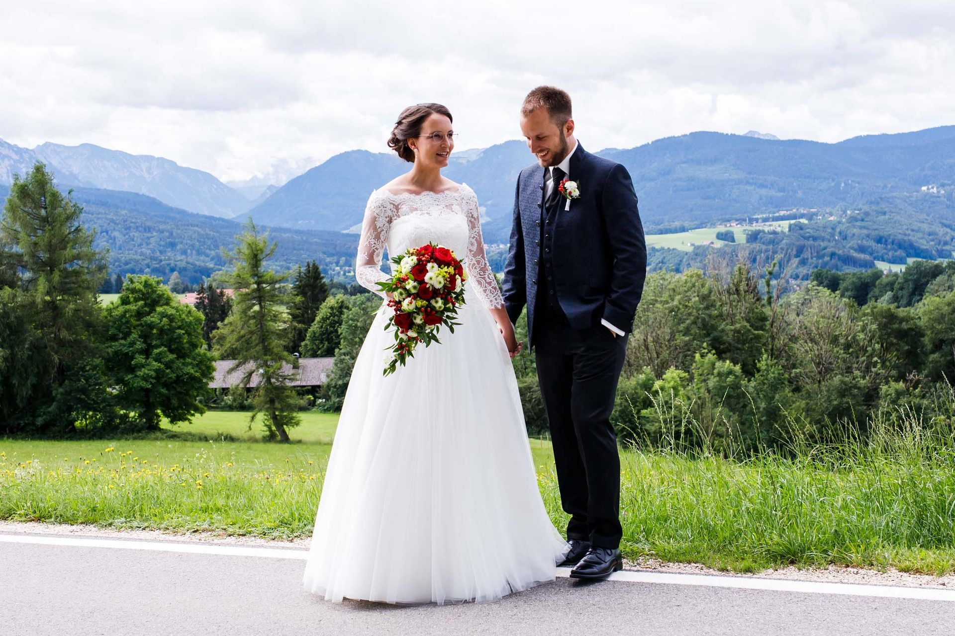 Brautpaar geht über wiese chiemgauer alpen im hintergrund