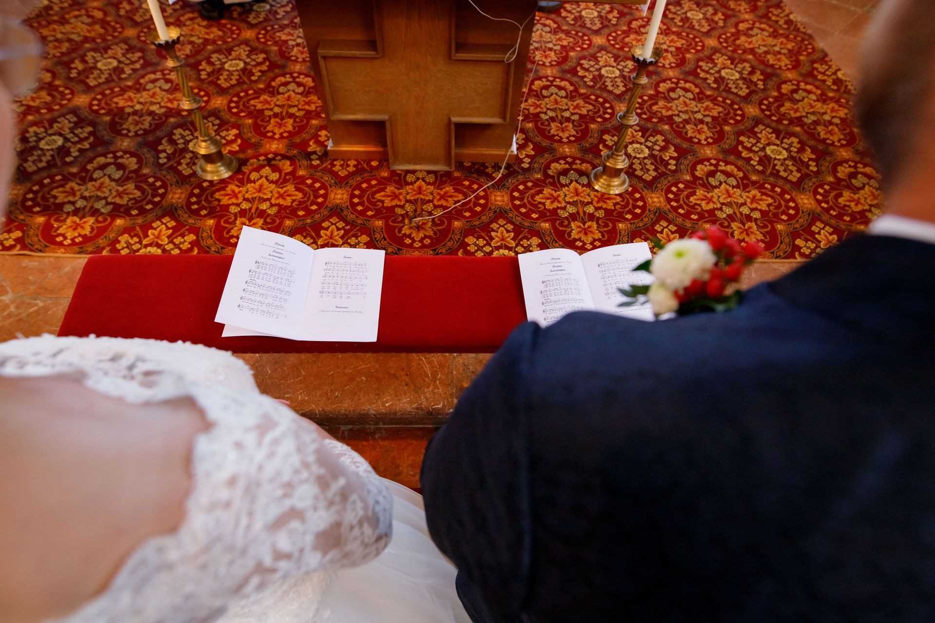 hochzeitsfotograf trauung kirche nussdorf liederhefte über die schulter des paares fotografiert
