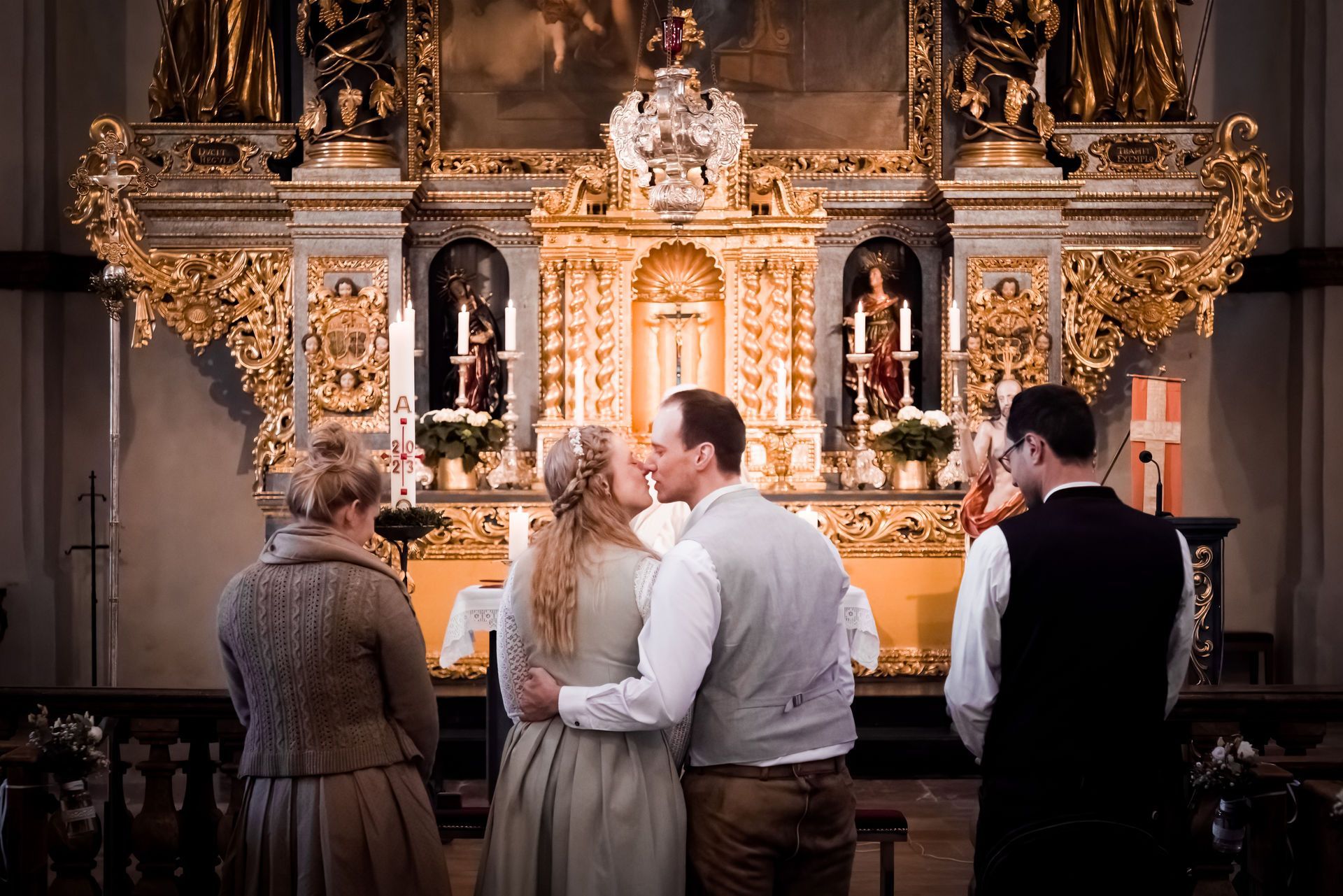 Die Braut wartet auf den Zustieg zum Schiff // Heiraten auf der Fraueninsel, Andrea Kühl 2023 brautpaar in tracht küsst sich vor dem altar bei hochzeit in der klosterkirche auf der fraueninsel.