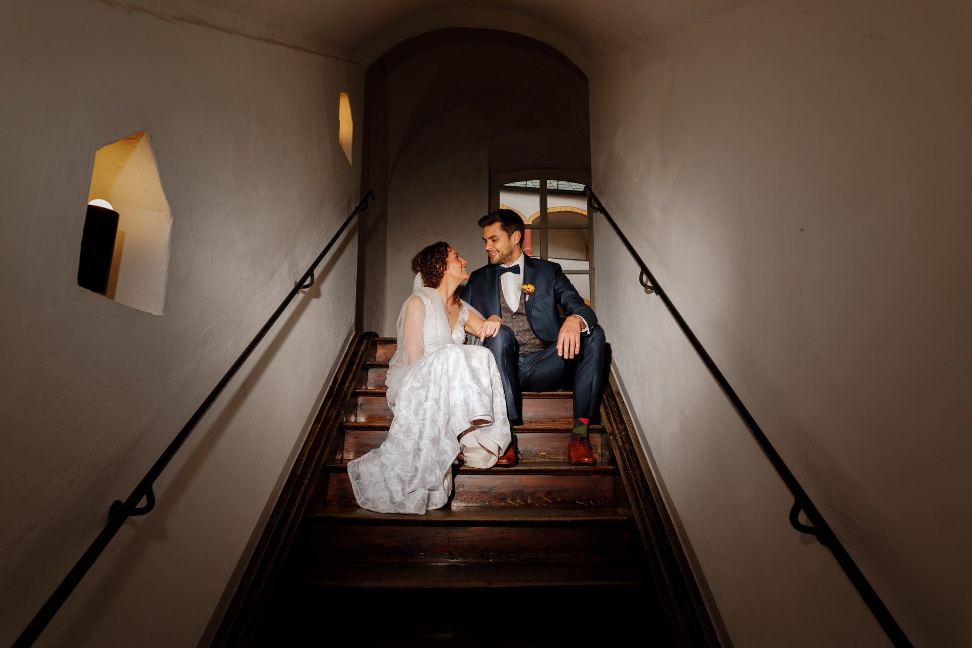 hochzeitspaar sitzt auf treppe in altem gebäude