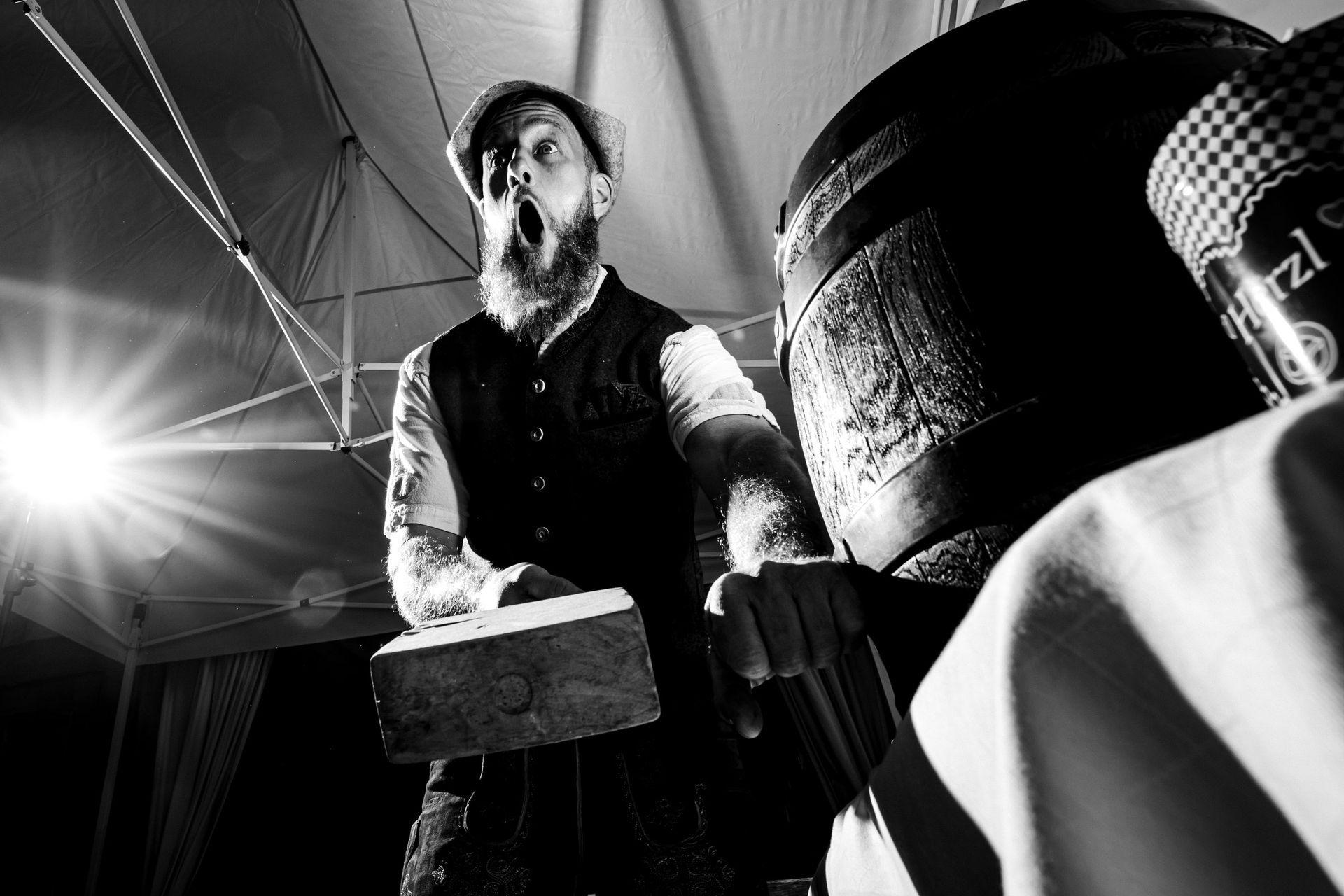 mann mit holzhammer kurz vor bierfassanstich