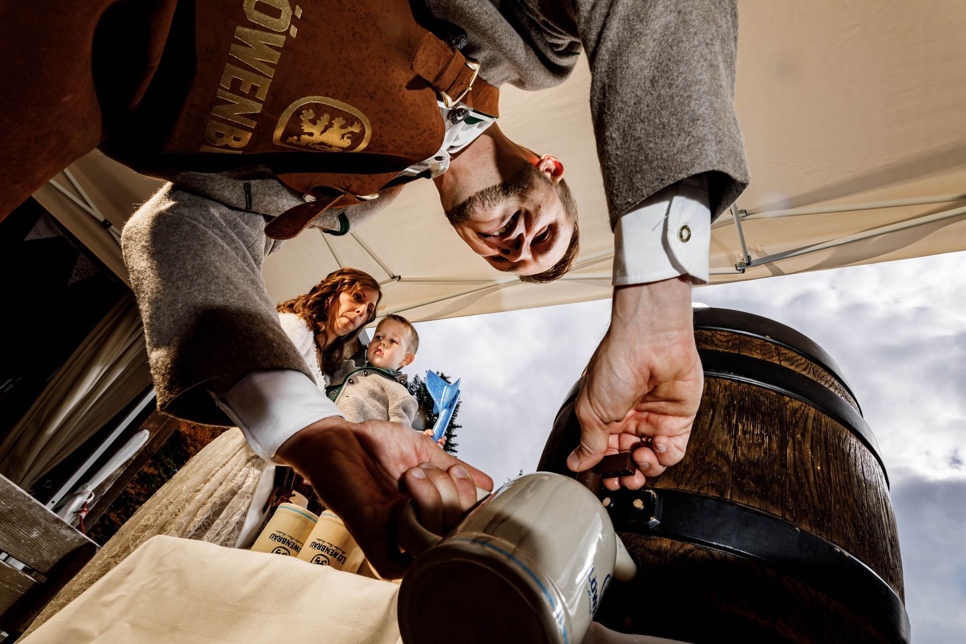 bierfassanstich im almbad huberspitz tiefe perspektive brautpaar mit kind