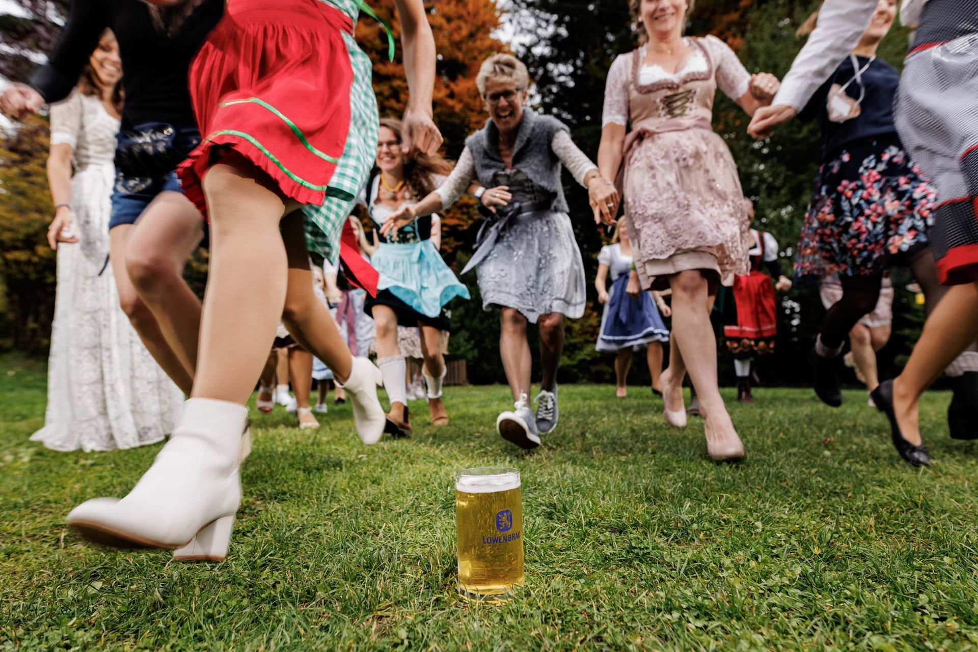 hochzeitsfeier im almbad huberspitz viele weibliche hochzeitsgaeste in tracht rennen um die wette für den gefüllten bierkrug