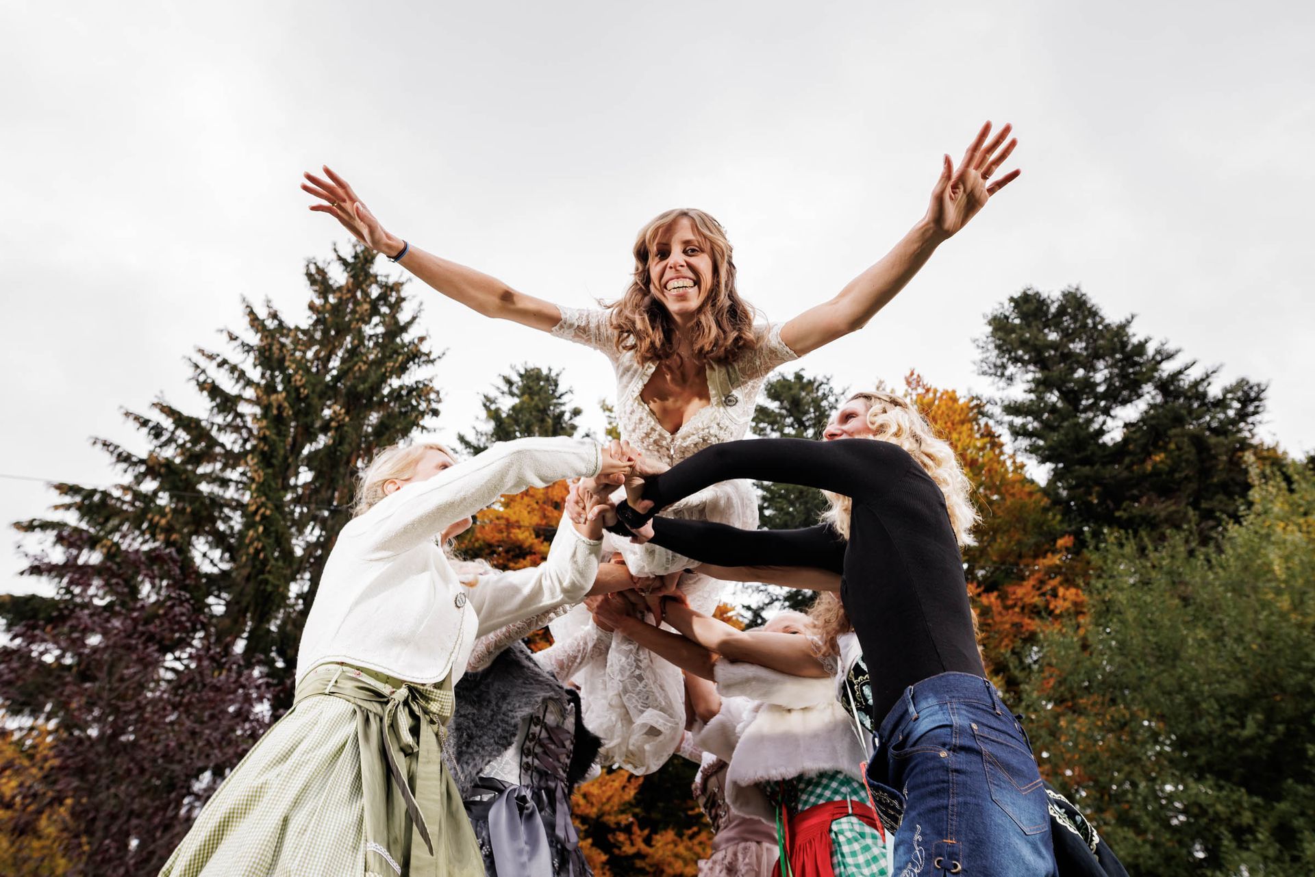hochzeitsfeier im almbad huberspitz viele weibliche hochzeitsgaeste in tracht werfen die braut in die luft