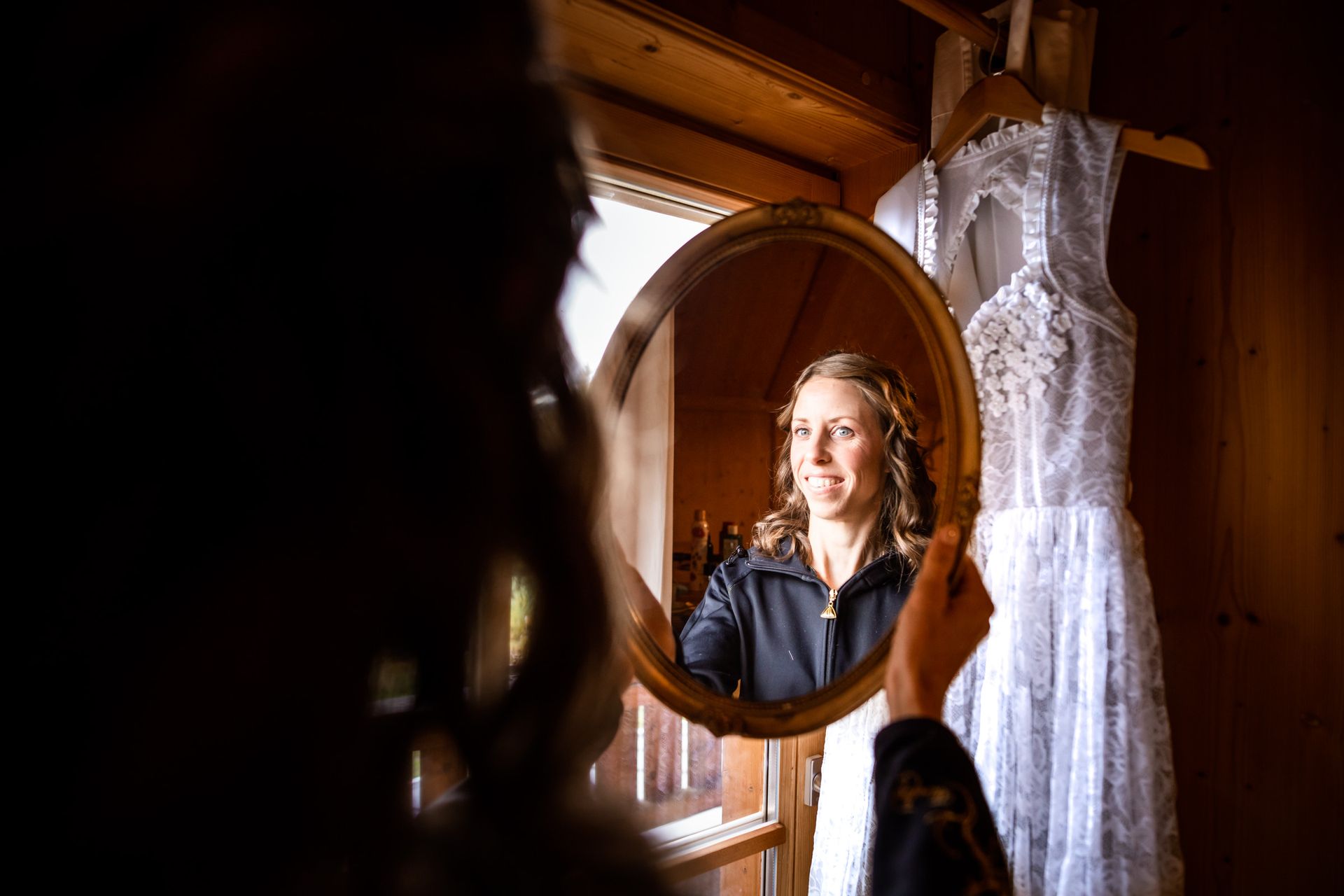 Braut schaut Spiegelbild in großem ovalen Spiegel brautkleid im hintergrund