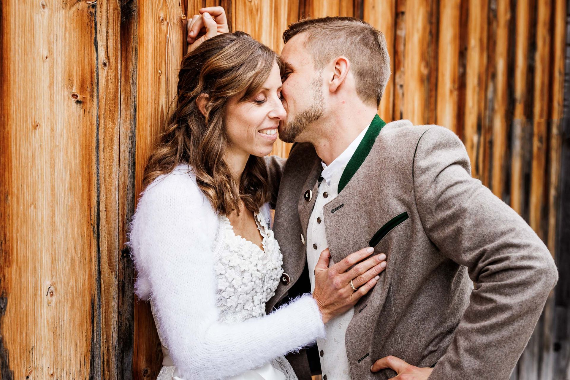 hochzeitsfeier im almbad huberspitz brautpaar steht vor holzwand