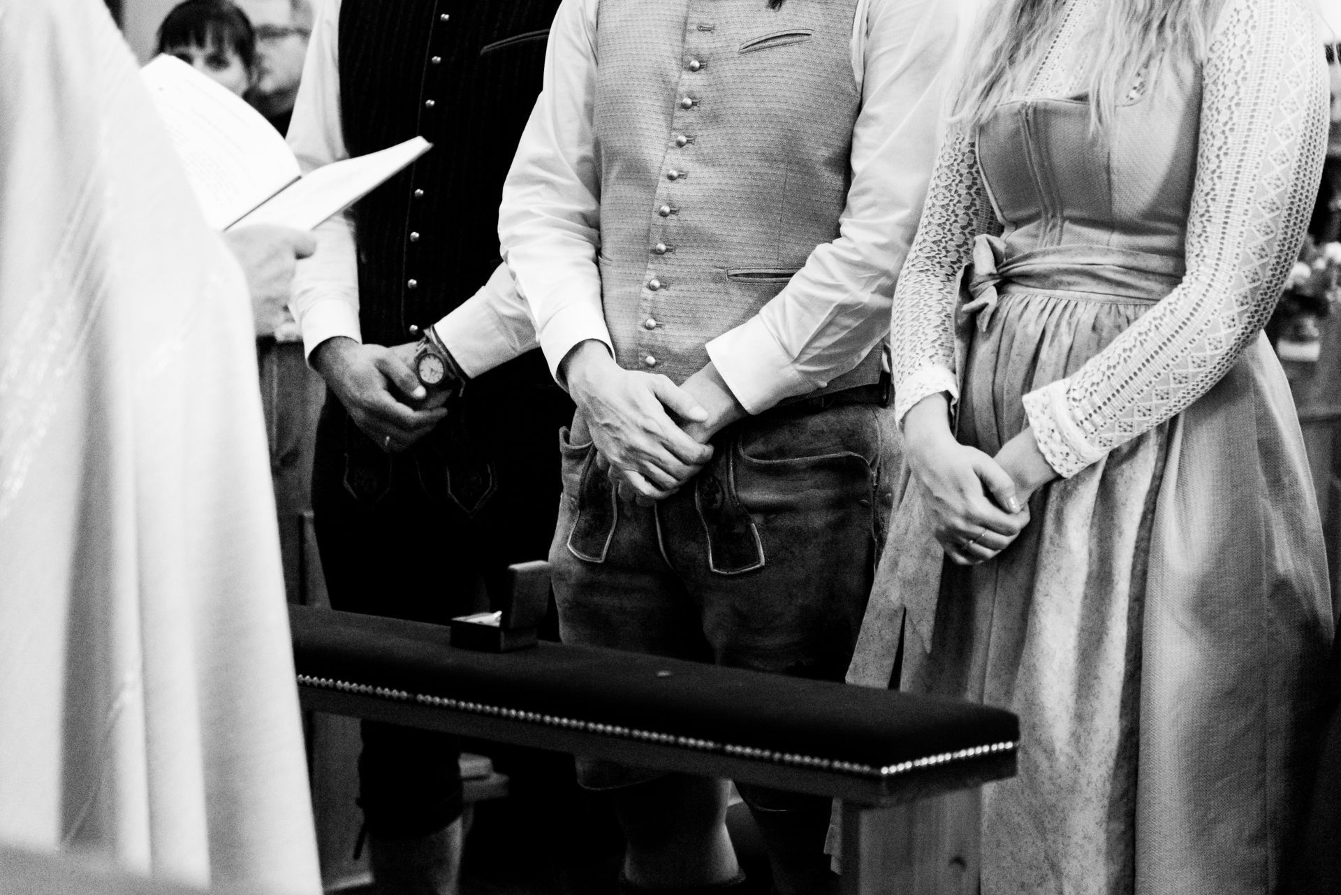 3 menschen stehen nebeneinander und falten hände bei kirchlicher hochzeit