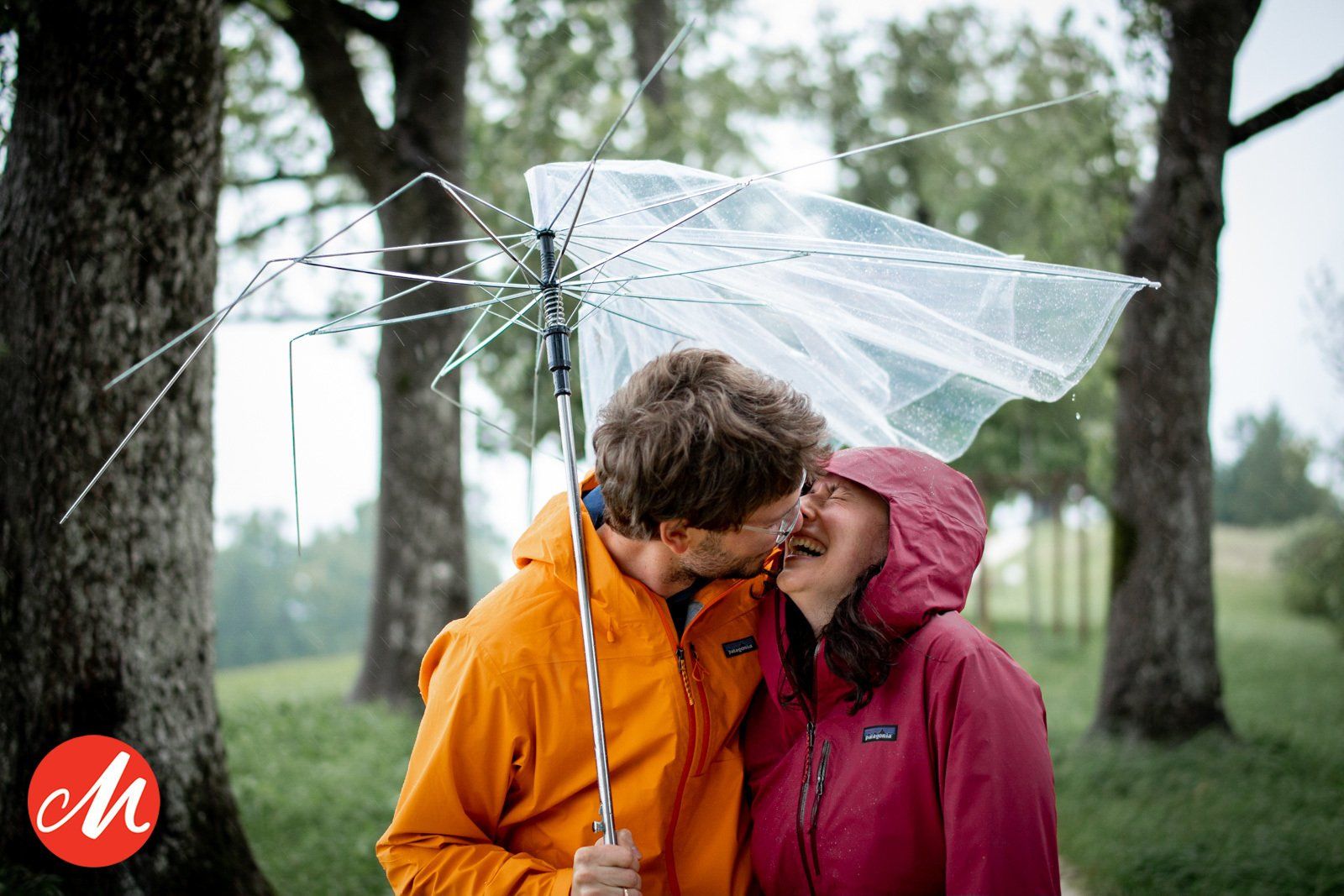 emotionaler moment paar lacht unter einem kaputten transparenten regenschirm