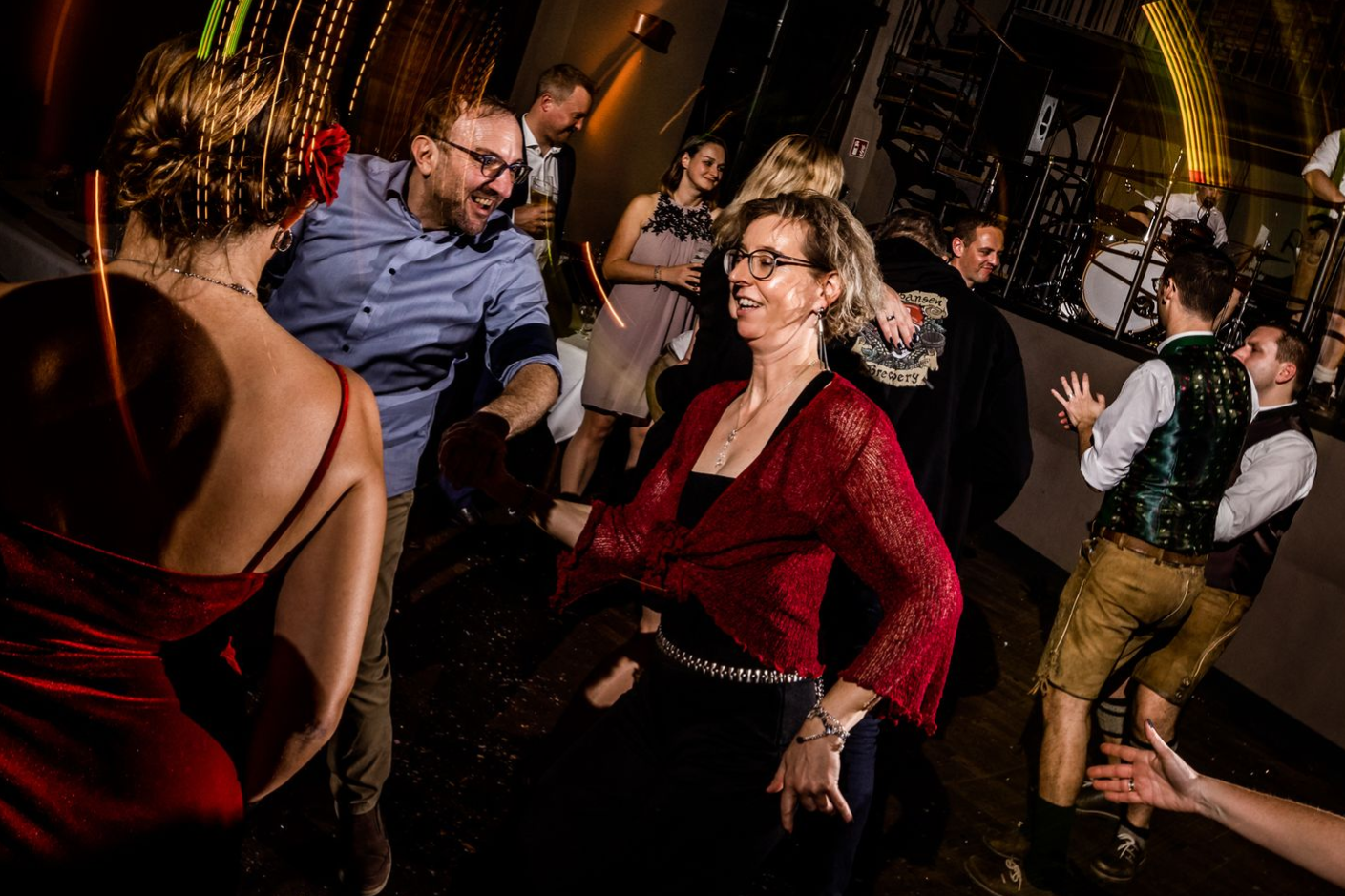 Ausgelassene Tanzszene auf einer Hochzeit: Ein lächelnder Mann und eine Frau tanzen dynamisch, umgeben von warmen Lichtspuren und kontrollierter Bewegungsunschärfe, die die Party-Atmosphäre einfangen.