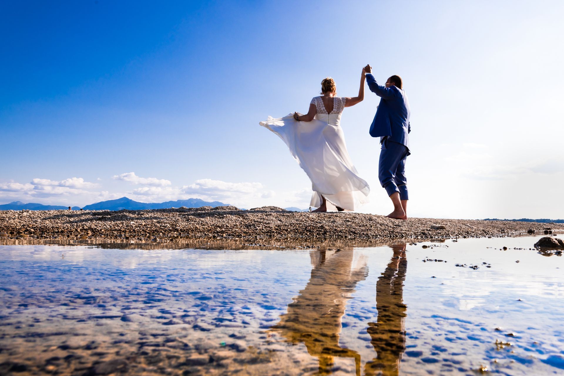 brautpaar tanzt auf kleiner sandbank im chiemsee mit wehendem brautkleid