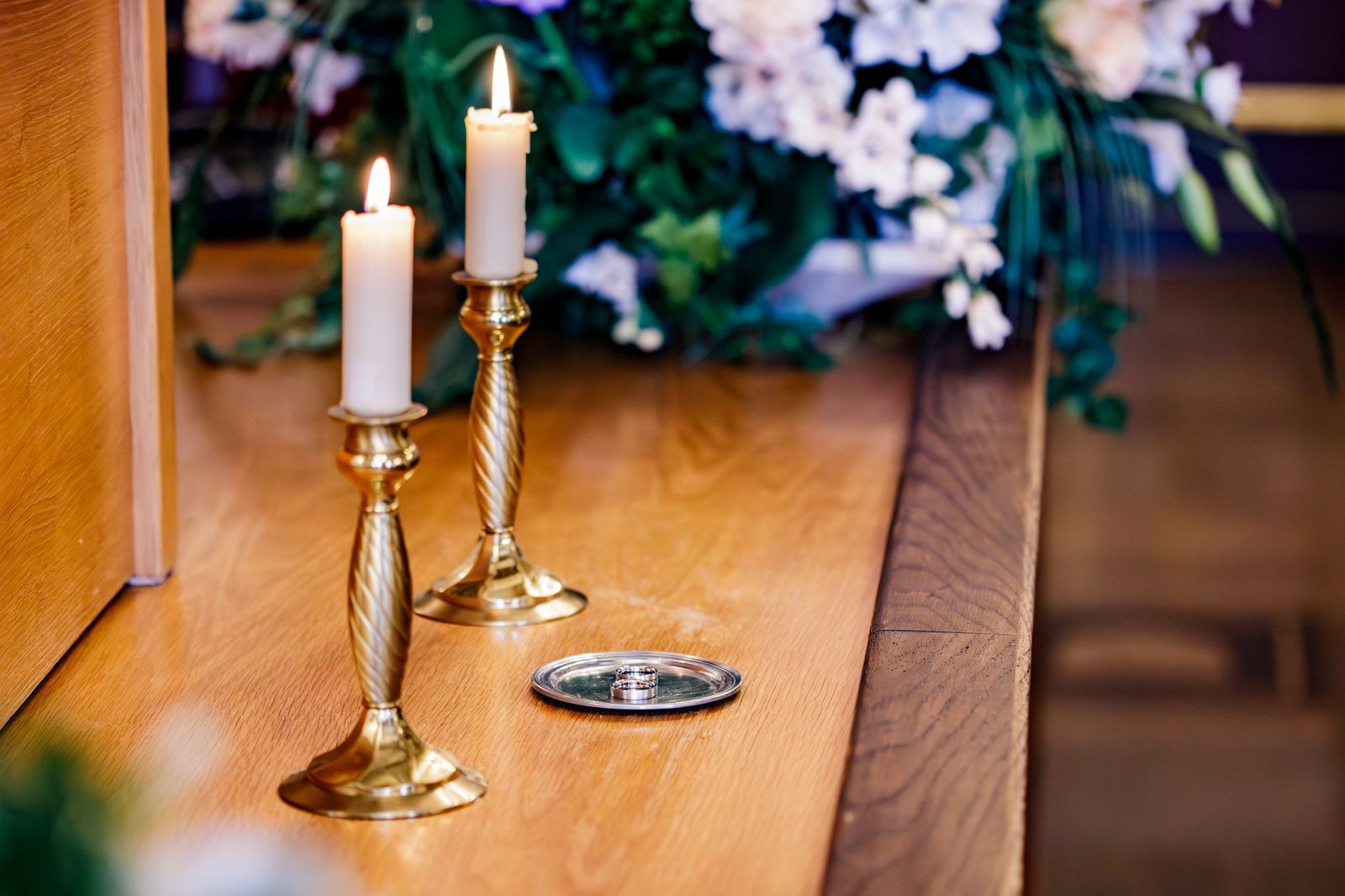 hochzeitsfotograf traunstein eheringe liegen auf kleinem metallteller zwischen 2 schmalenkerzen
