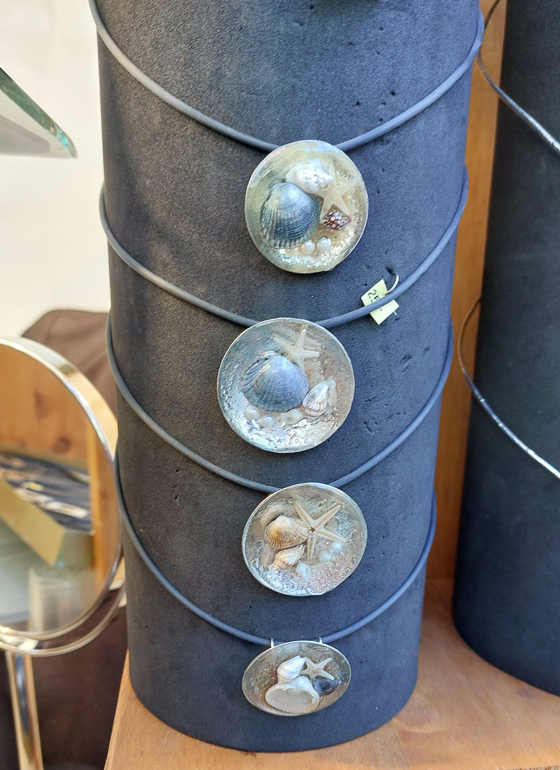 Übereinander an einem blauen Ständer aufgehängte Ketten mit Schmuckelementen