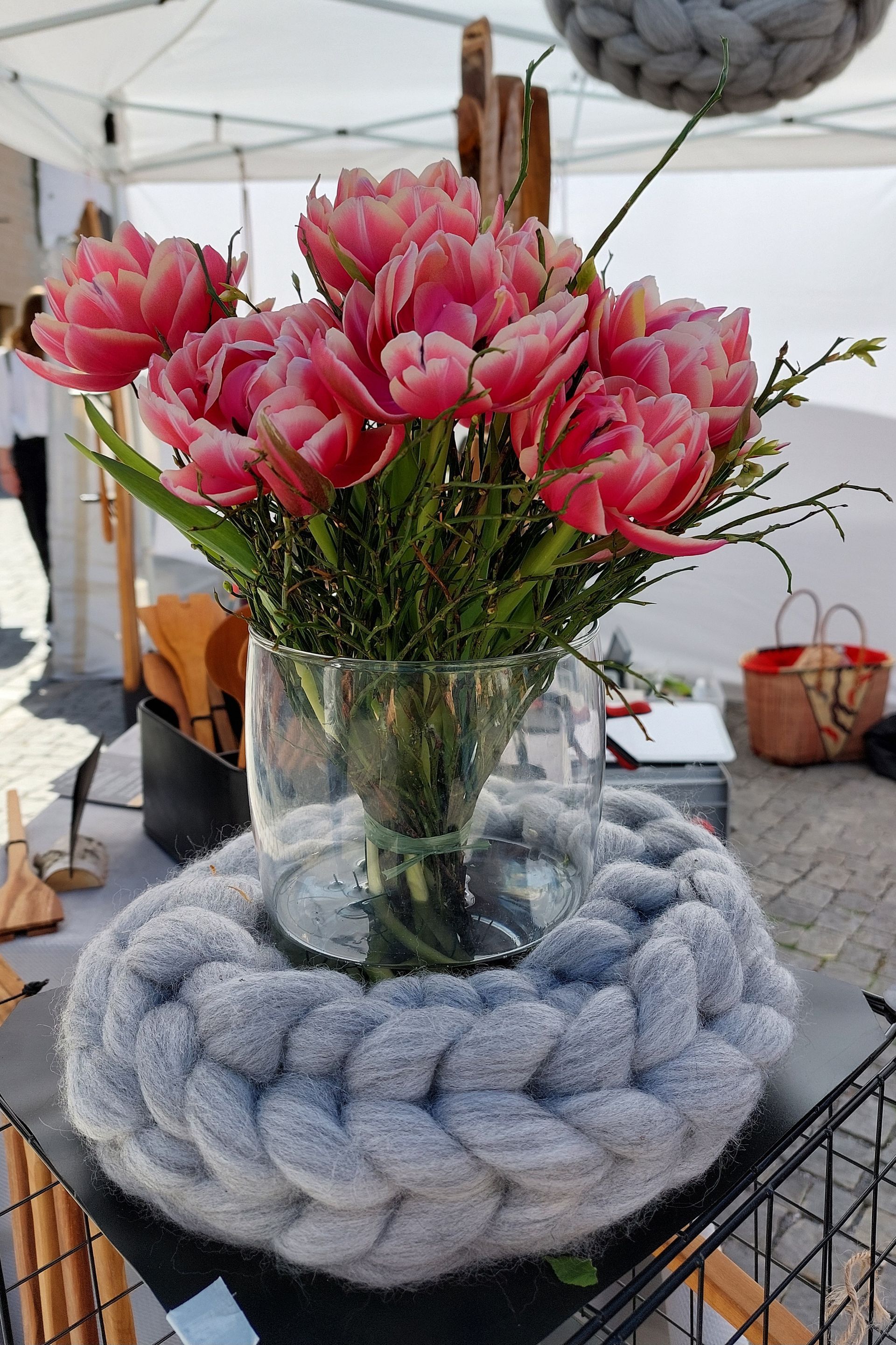 geflochtener grauer Wollkranz und Glasvase mit rosafarbenen Tulpen