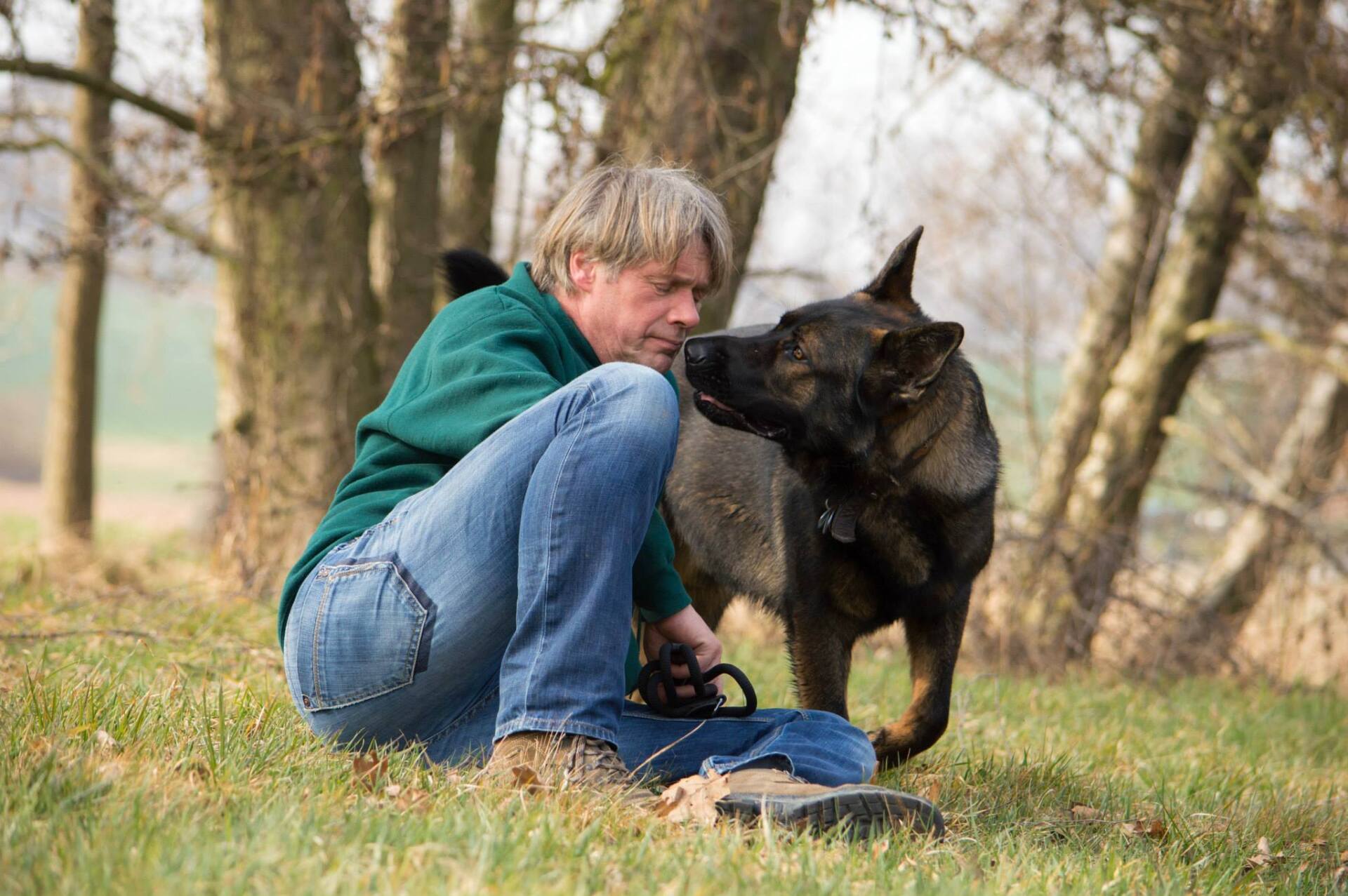 Ein großer grauer Schäferhundund sein züchter.