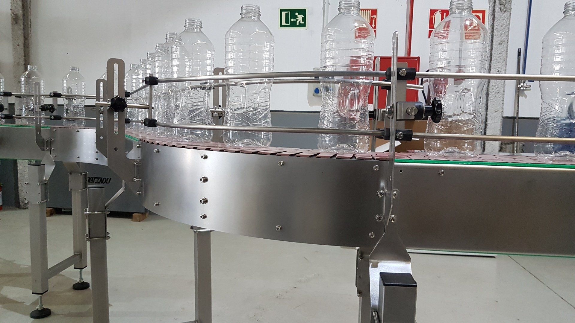 Transportador curvo de charnela para botellas o envases vacíos.
