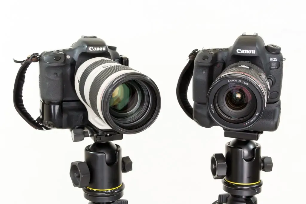 Two professional cameras next to each other on stands against a clean, white background