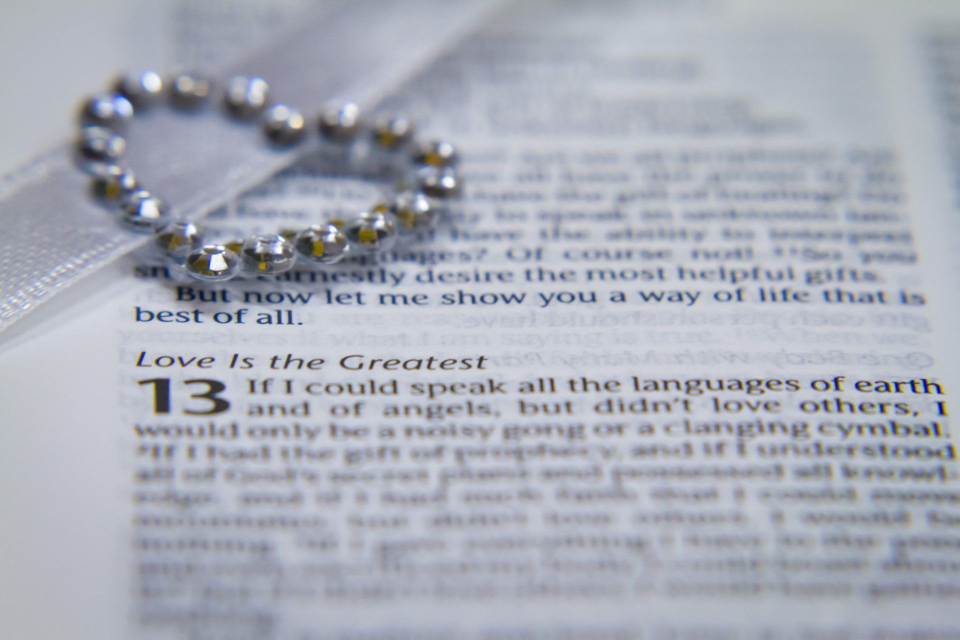 An image of a wedding pendant on a bible opened to a particular wedding verse
