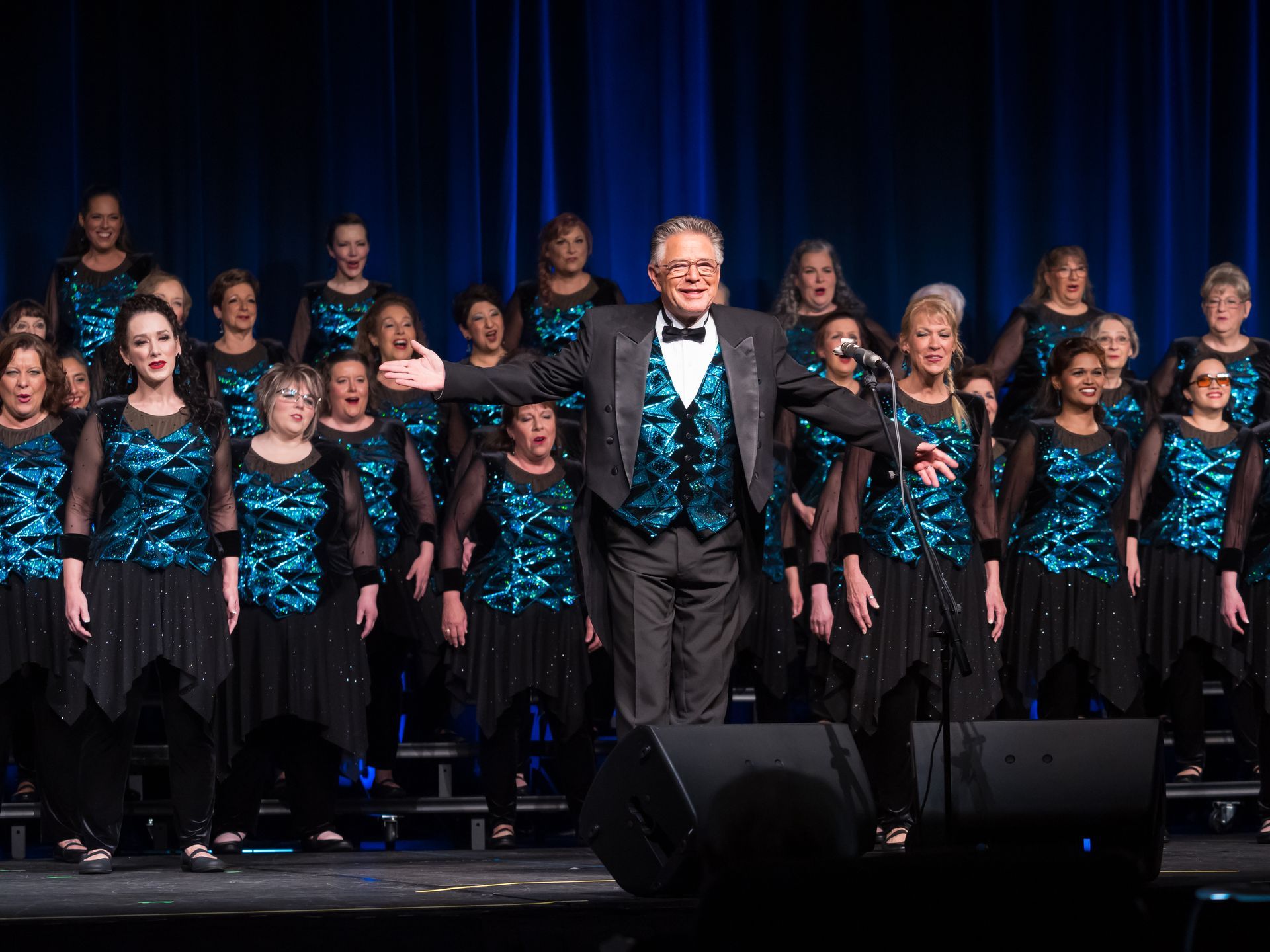 A chorus on stage with their conductor.