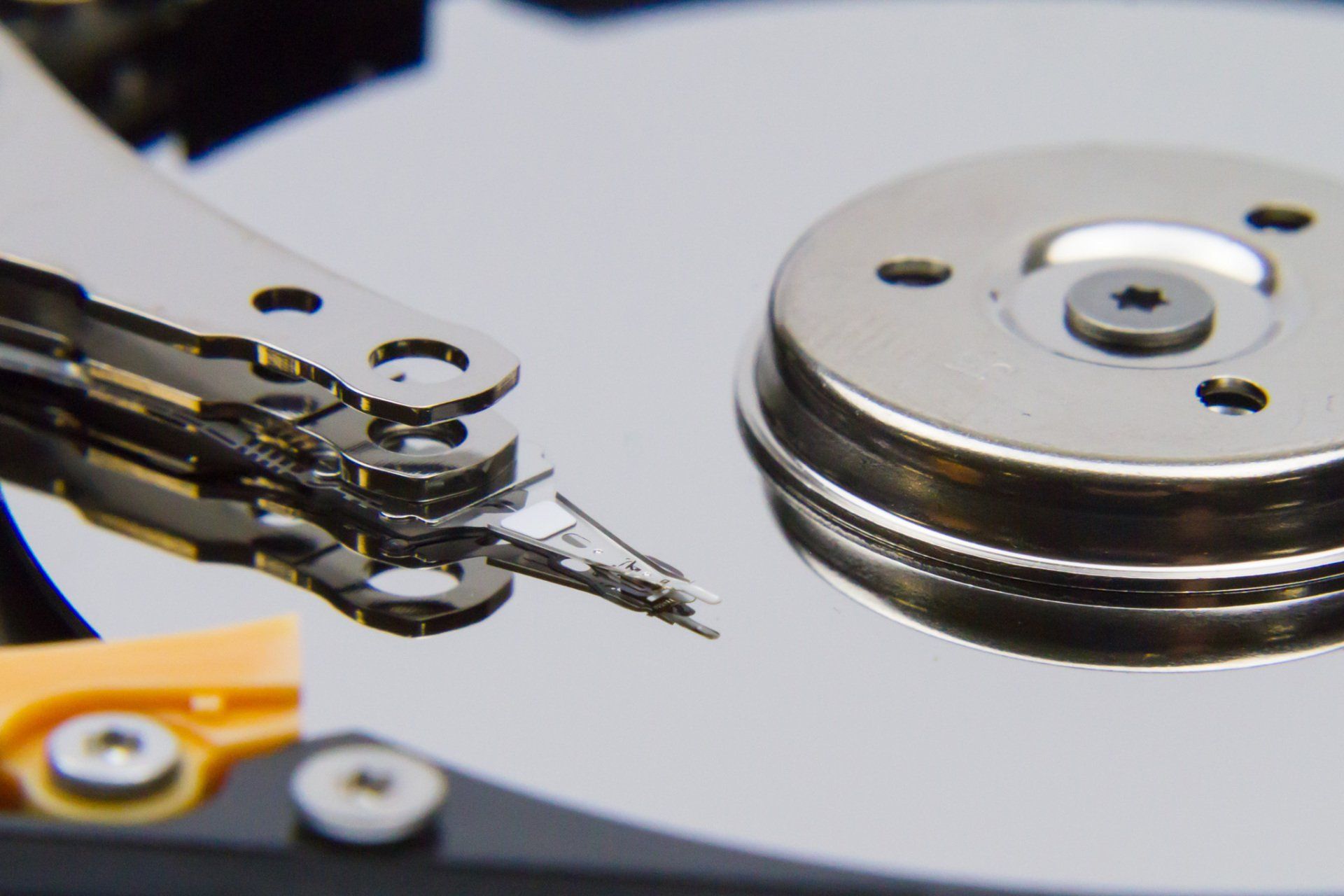 The inside view of a computer hard drive showing the disk platter and read write arm.