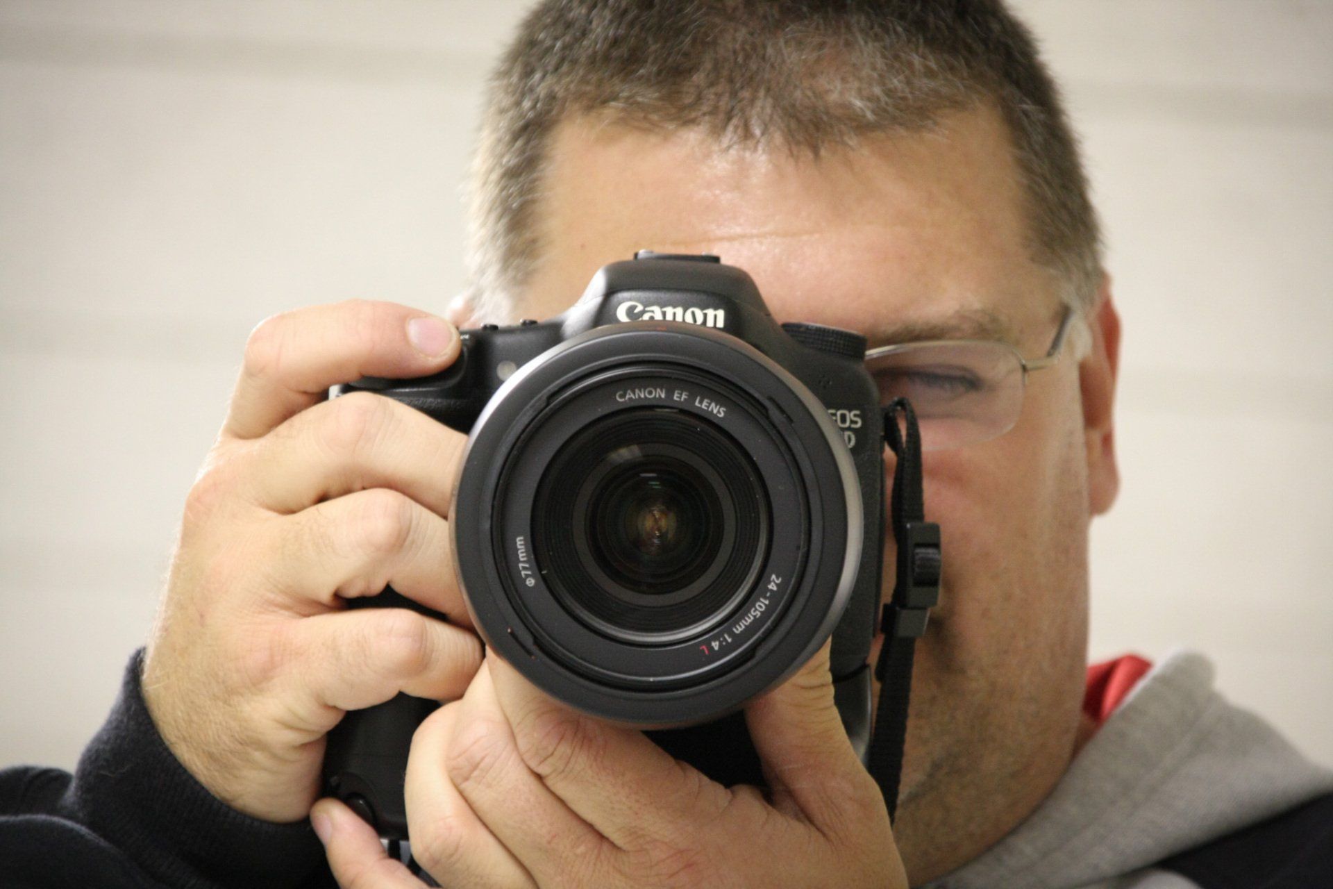 A man holding a camera and pointing it at the viewer preparing to take a photograph.